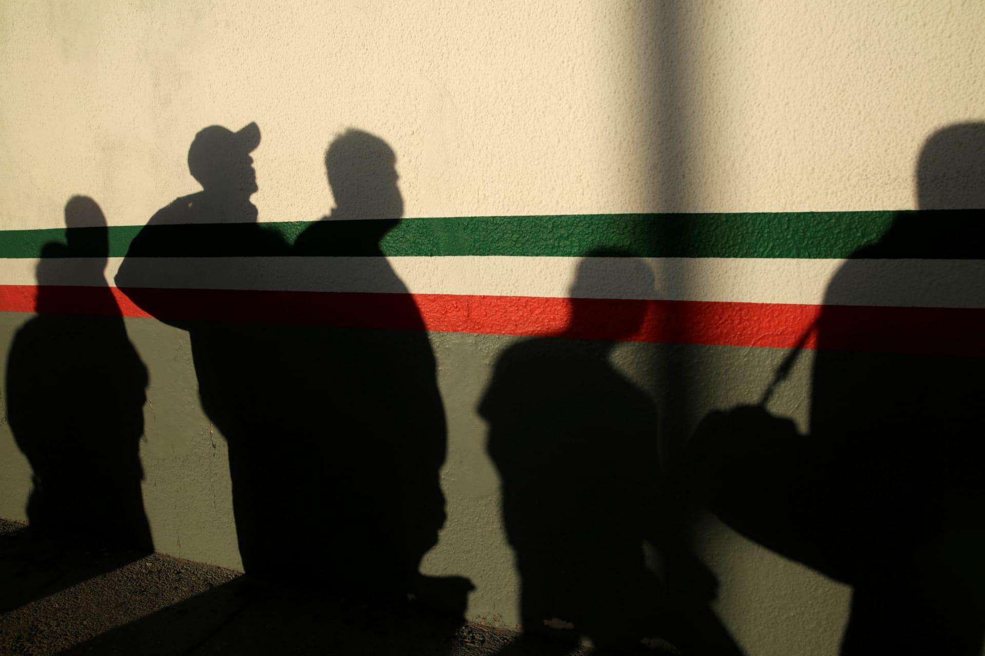 <p>After being deported from the United States, Mexican immigrants cast shadows on a National Institute of Migration (INM) building in Ciudad Juarez, Mexico, on April 21, 2020.</p>
