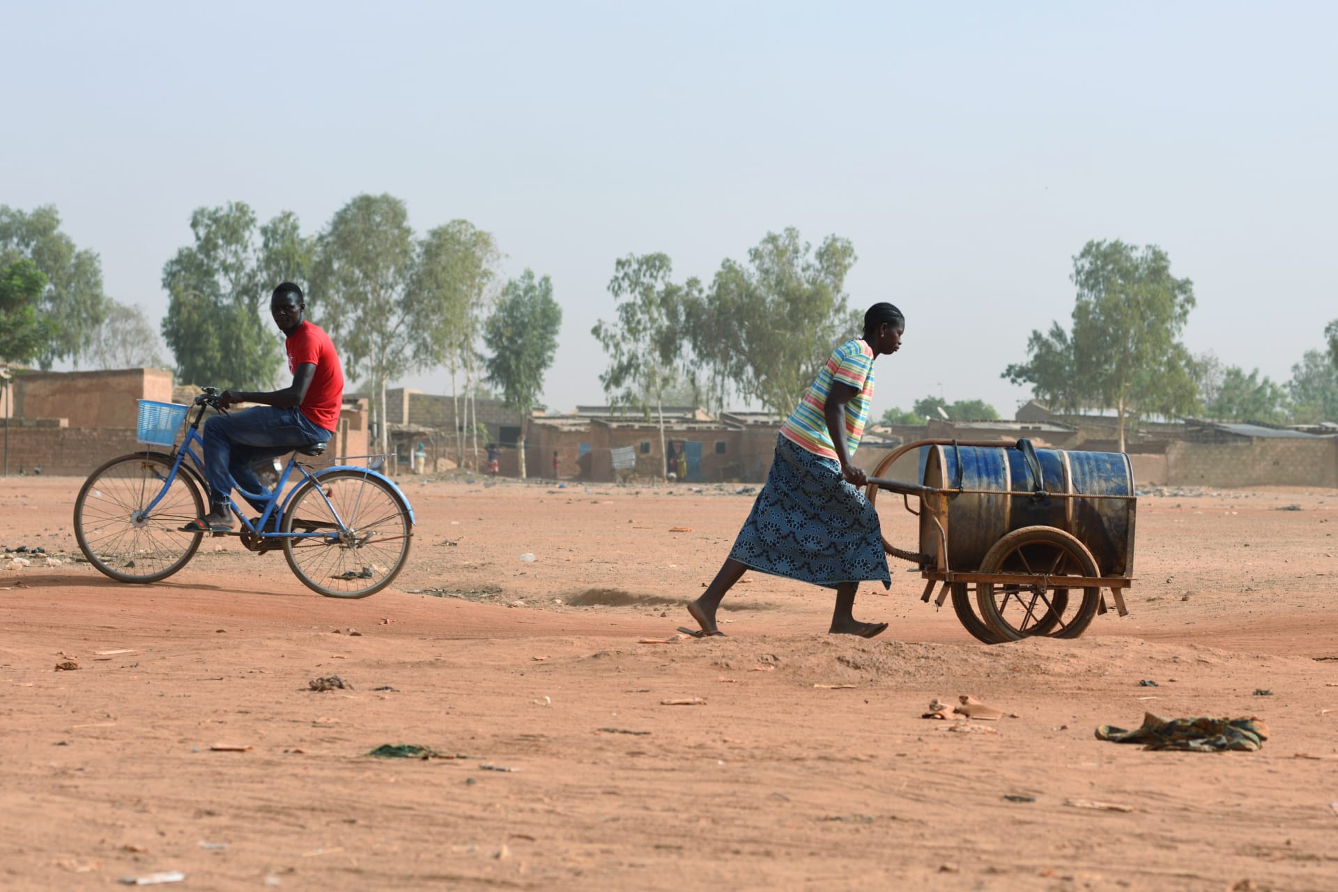 <p>A woman pushes a barrel filled with water she bought from a privately-owned water tower, amid an outbreak of the coronavirus disease (COVID-19), in Taabtenga district of Ouagadougou, Burkina Faso, on April 3, 2020.</p>
