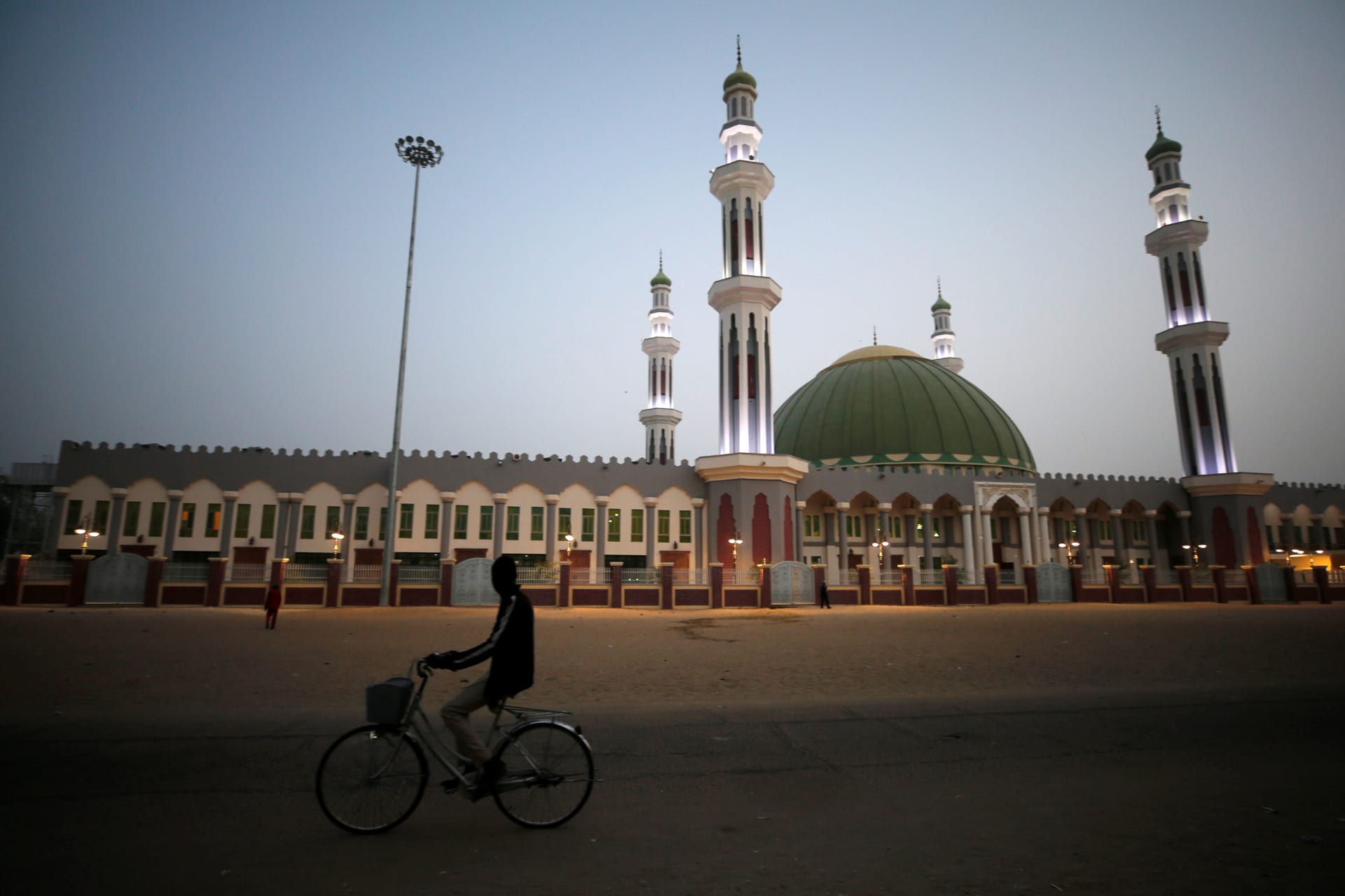<p>A man cycles past the Al Ansar mosque in Maiduguri, Nigeria, on February 16, 2019. Both Yusuf and Adam preached there in the early 2000s.</p>
