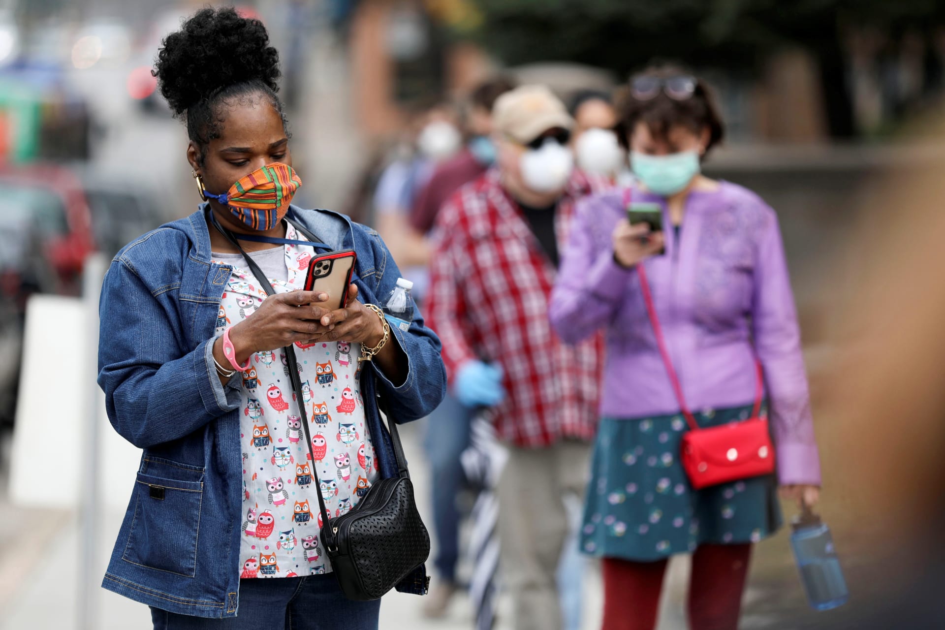 <p>Marni Bailey, a worker at a group home for the elderly, stands in line outside Riverside University High School to vote in the presidential primary election held amid the coronavirus (COVID-19) outbreak. Milwaukee, Wisconsin, United States. April 7, 2020.</p>
