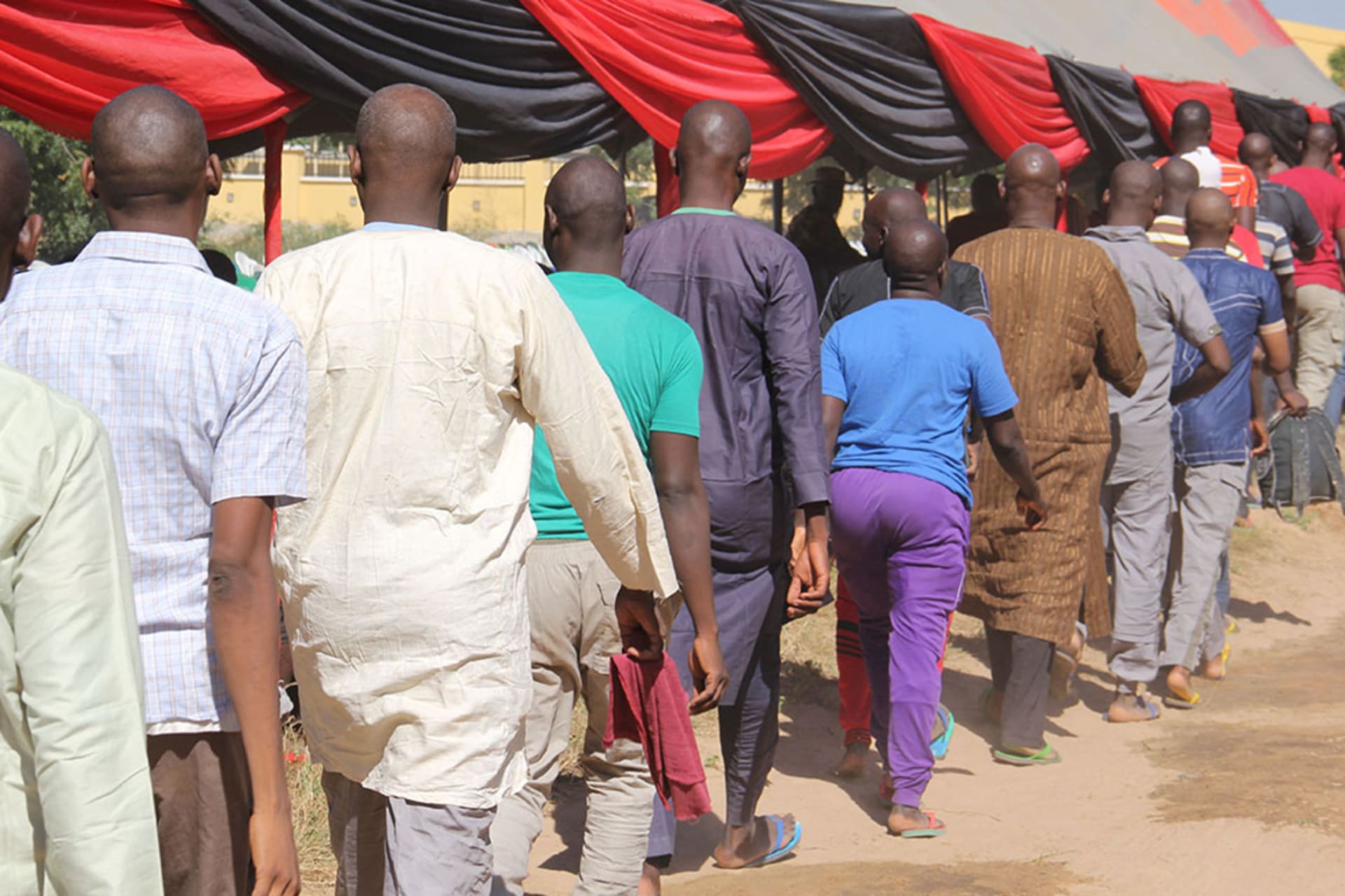 <p>Freed inmates walk in a line after they were released to state officials for rehabilitation and integration after they were detained for up to four years over suspicion of links with Boko Haram at an official ceremony in Maiduguri, on November 27, 2019.</p>
