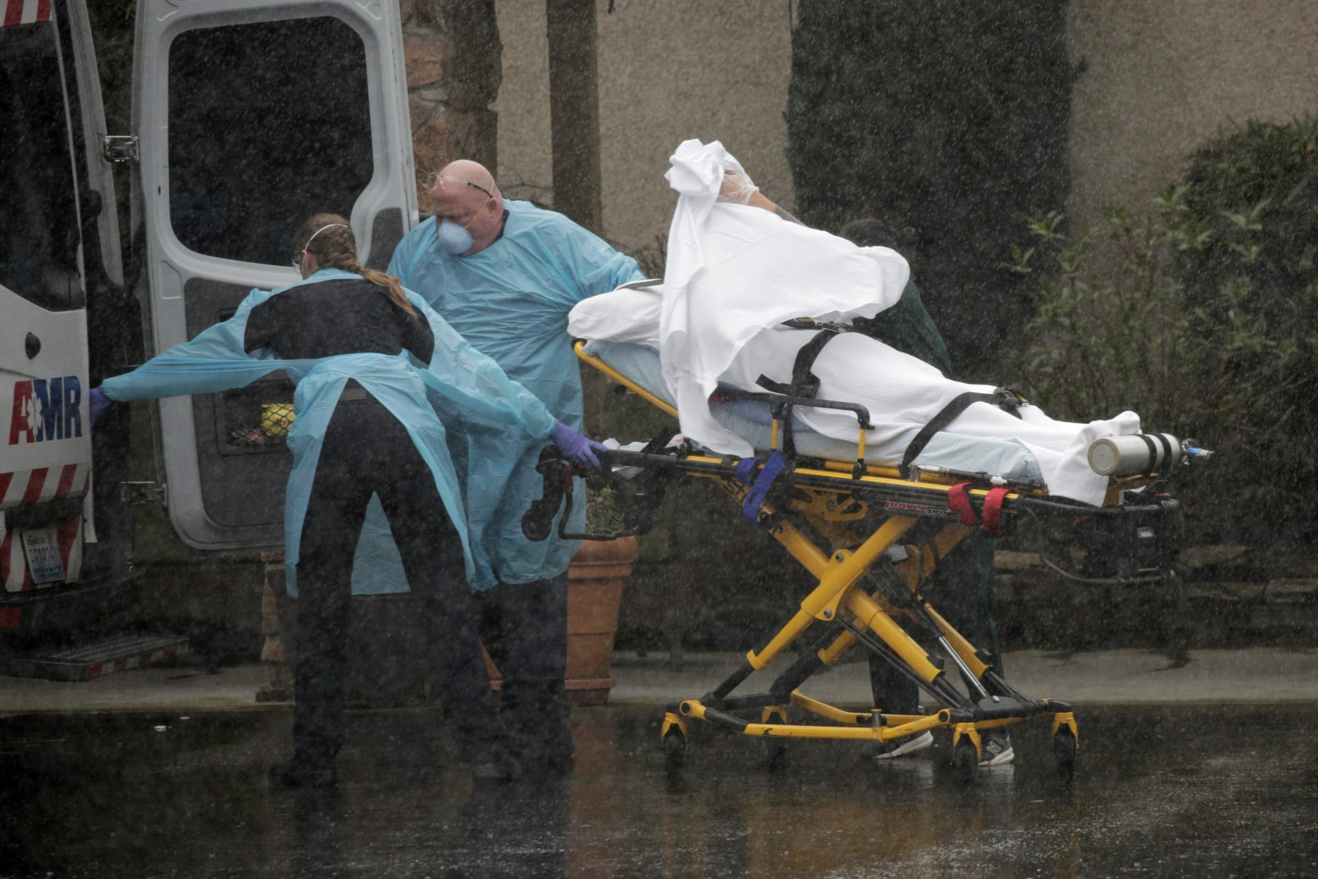 <p>Medics transport a patient through heavy rain into an ambulance at Life Care Center of Kirkland.</p>
