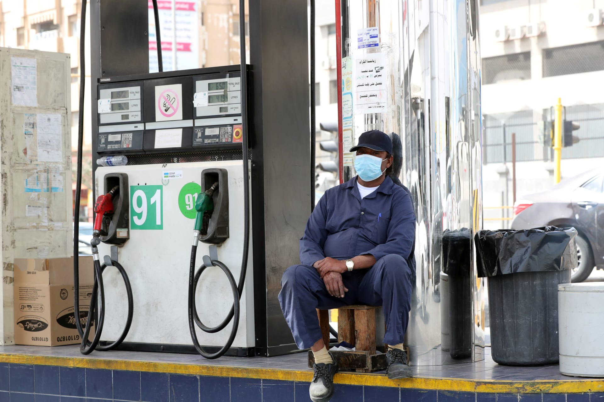<p>A gas station worker wearing a protective face mask sits next to a petrol station, after Saudi Arabia imposed a temporary lockdown on the province of Qatif following the spread of coronavirus, in Qatif, Saudi Arabia March 9, 2020.</p>
