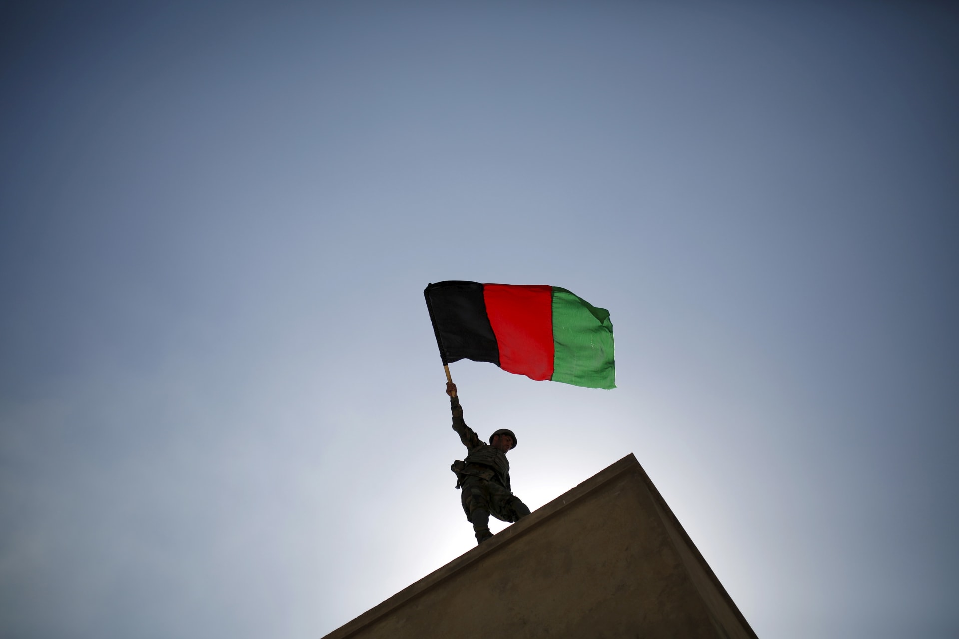 <p>An Afghan National Army officer holds the Afghan flag during a training exercise in Kabul in October 2015.</p>
