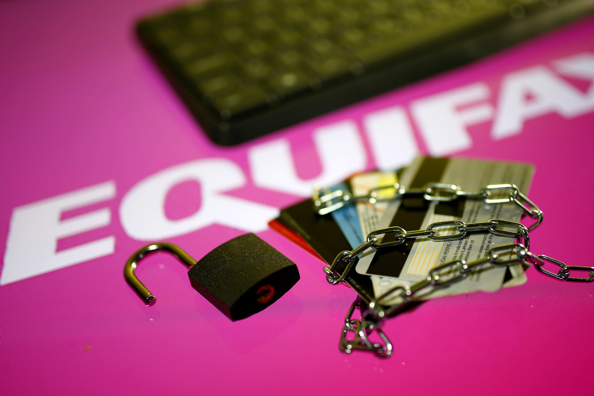 <p>Credit cards, a chain and an open padlock is seen in front of displayed Equifax logo</p>
