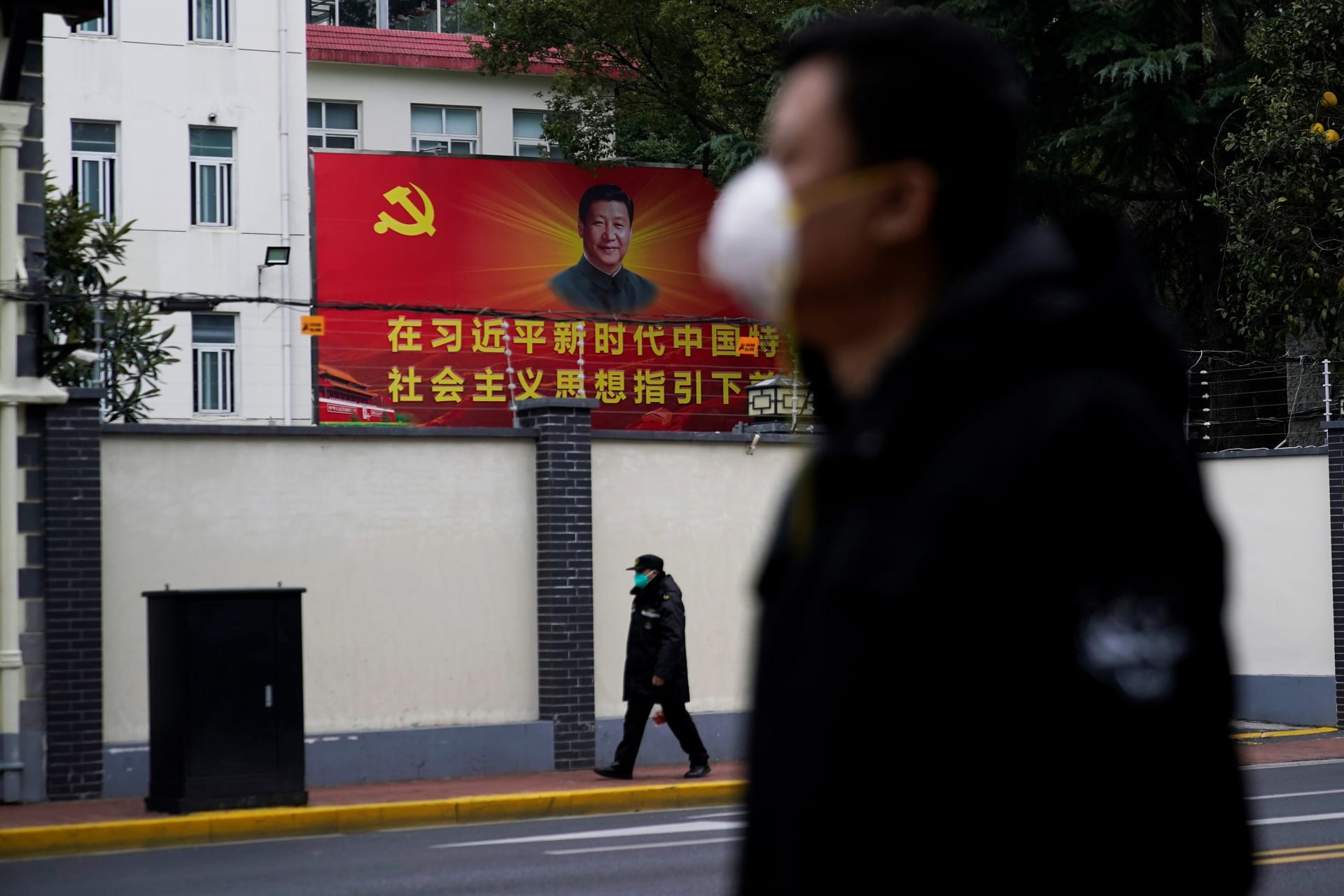 <p>People wearing masks walk past a portrait of Chinese President Xi Jinping on a street as the country is hit by an outbreak of the novel coronavirus in Shanghai.</p>

