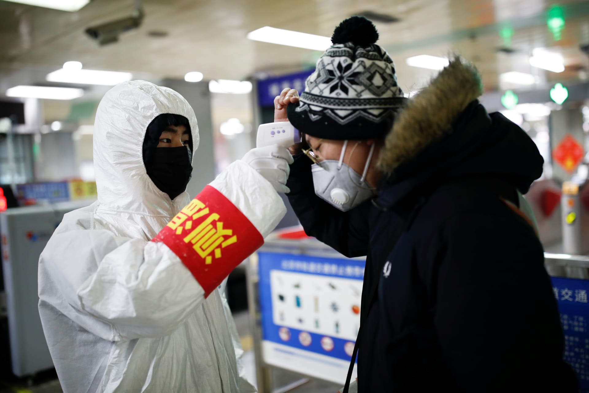 <p>A staff member checks the temperature of a passenger entering a subway station, as the country is hit by an outbreak of the new coronavirus, in Beijing, China</p>