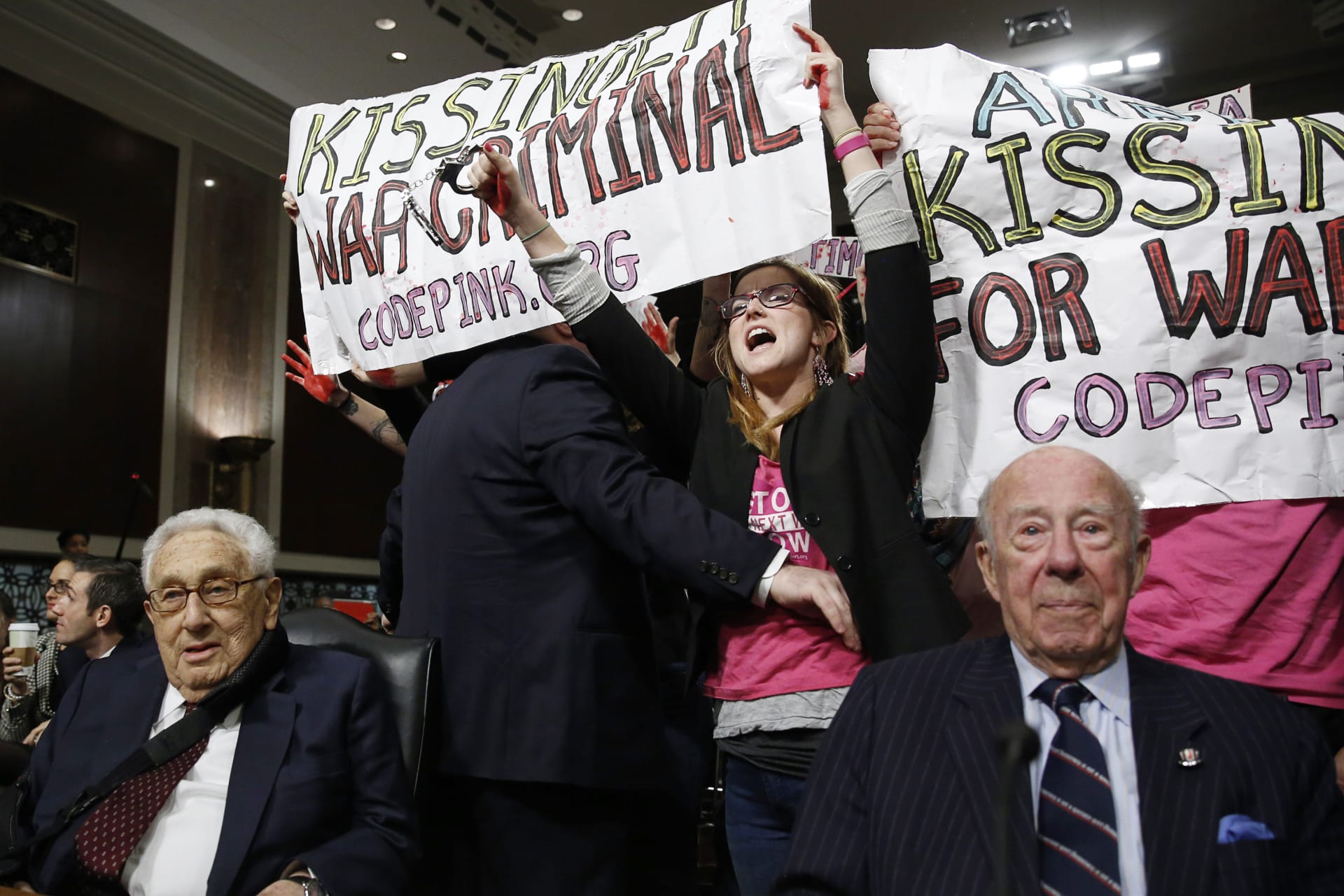 <p>Code Pink demonstrators surround former United States Secretaries of State Henry Kissinger (L) and George Shultz (R) before the beginning of the Senate Armed Services Committee on global challenges and U.S. national security strategy on Capitol Hill</p>
