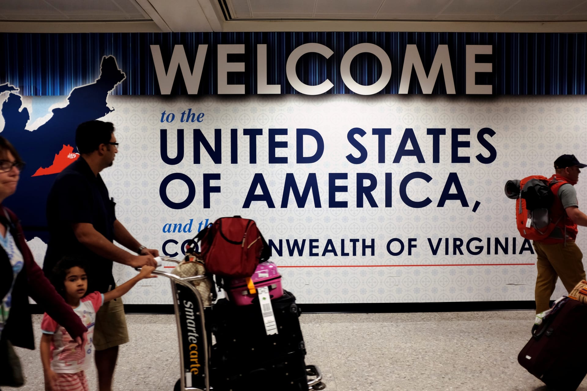 <p>A family exits after clearing immigration and customs at Dulles International Airport in Dulles, Virginia, United States, on September 24, 2017. </p>