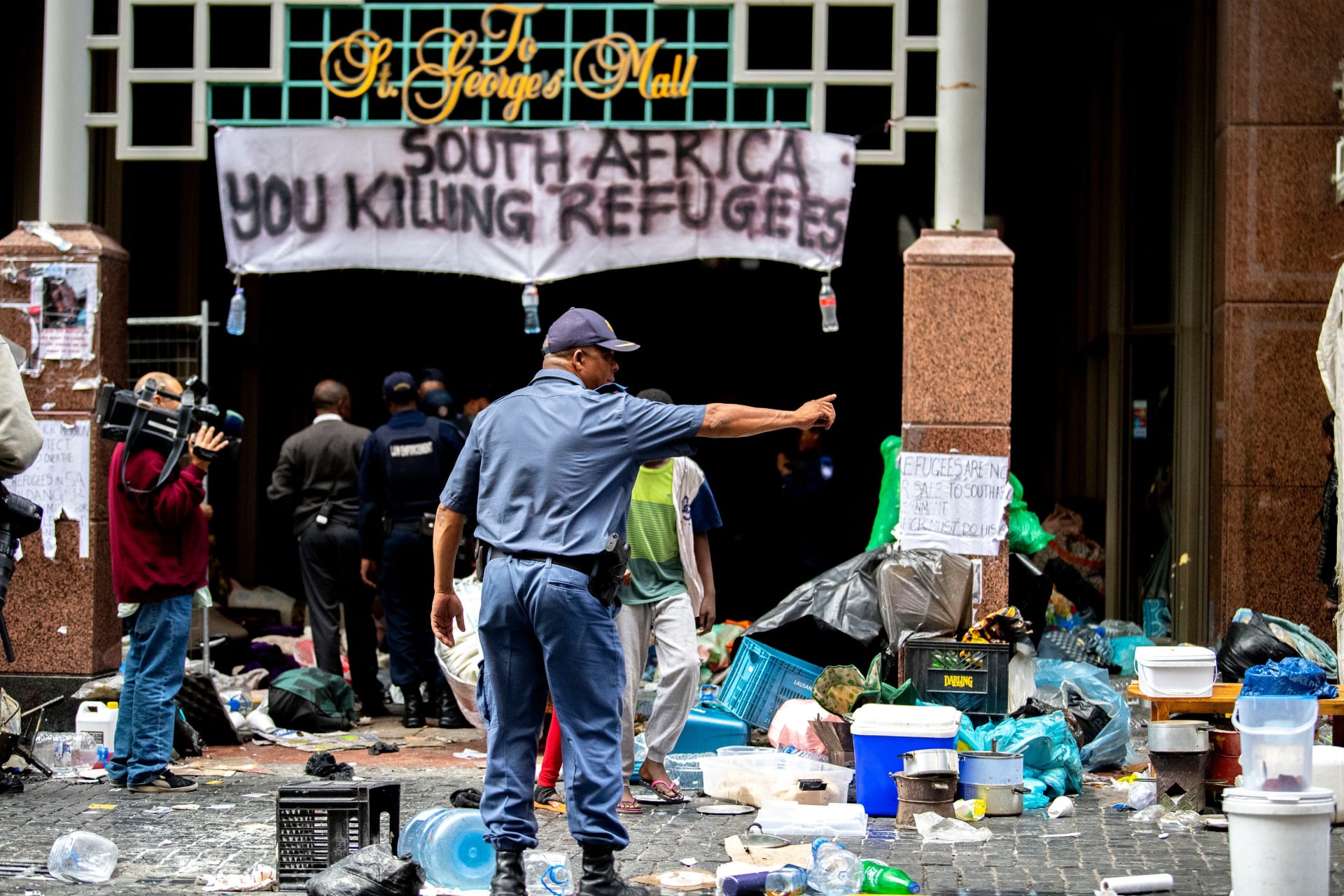 <p>South African police officer gestures as they forcefully remove refugees from various countries who were camping outside the Cape Town offices of the United Nations Council for Refugees, in Cape Town on October 30, 2019.</p>

