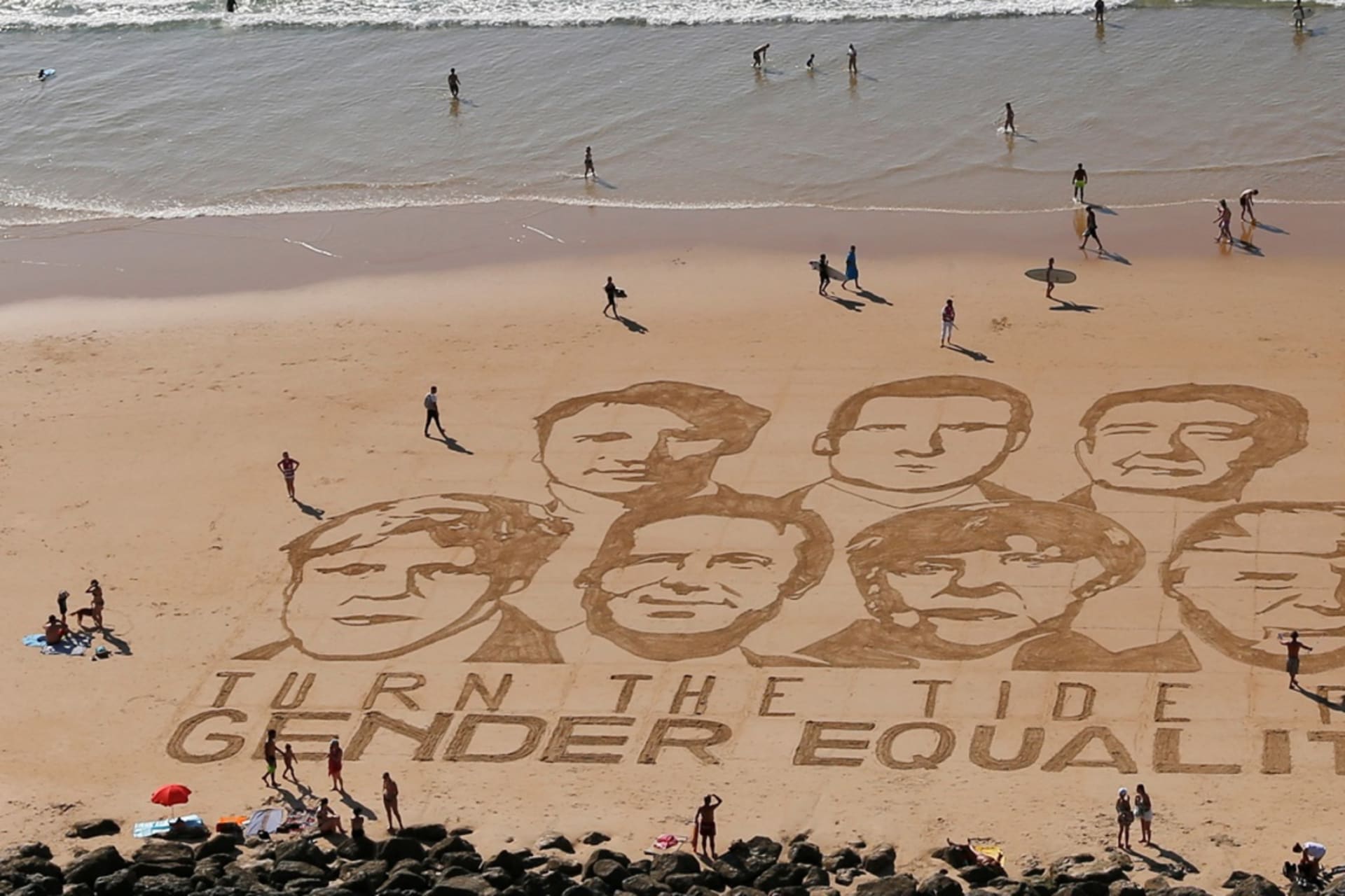 <p>The faces of the G7 leaders are drawn in sand with the message “Turn the Tide for Gender Equality.”</p>
