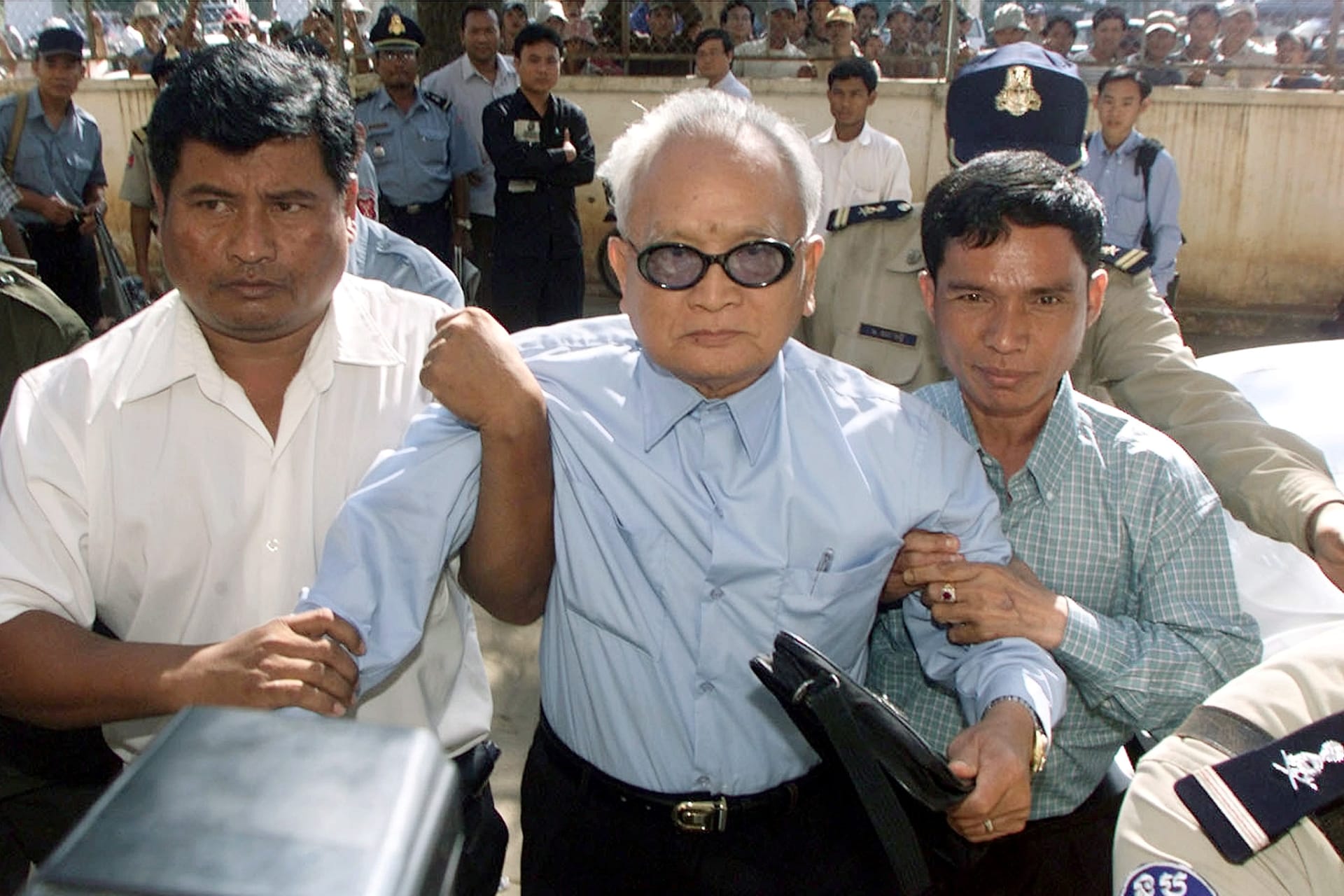 <p>The Khmer Rouge’s most senior surviving leader, “Brother Number Two” Nuon Chea, is held as he approaches the municipal court in the Cambodian capital Phnom Penh on December 13, 2002.</p>
