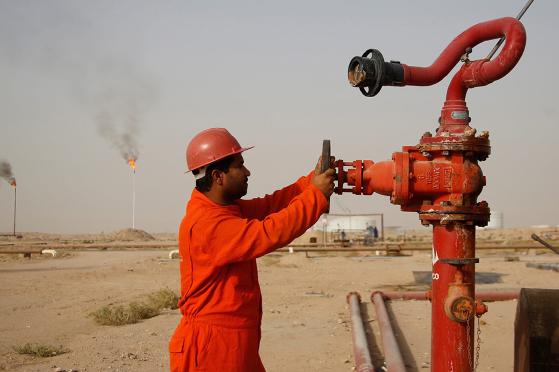 <p>A worker adjusts the valve of an oil pipe at a refinery in Najaf, Iraq.</p>
