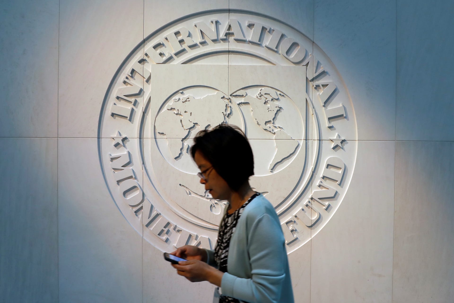 <p>A woman walks past the International Monetary Fund (IMF) logo at its headquarters in Washington, U.S., May 10, 2018. </p>
