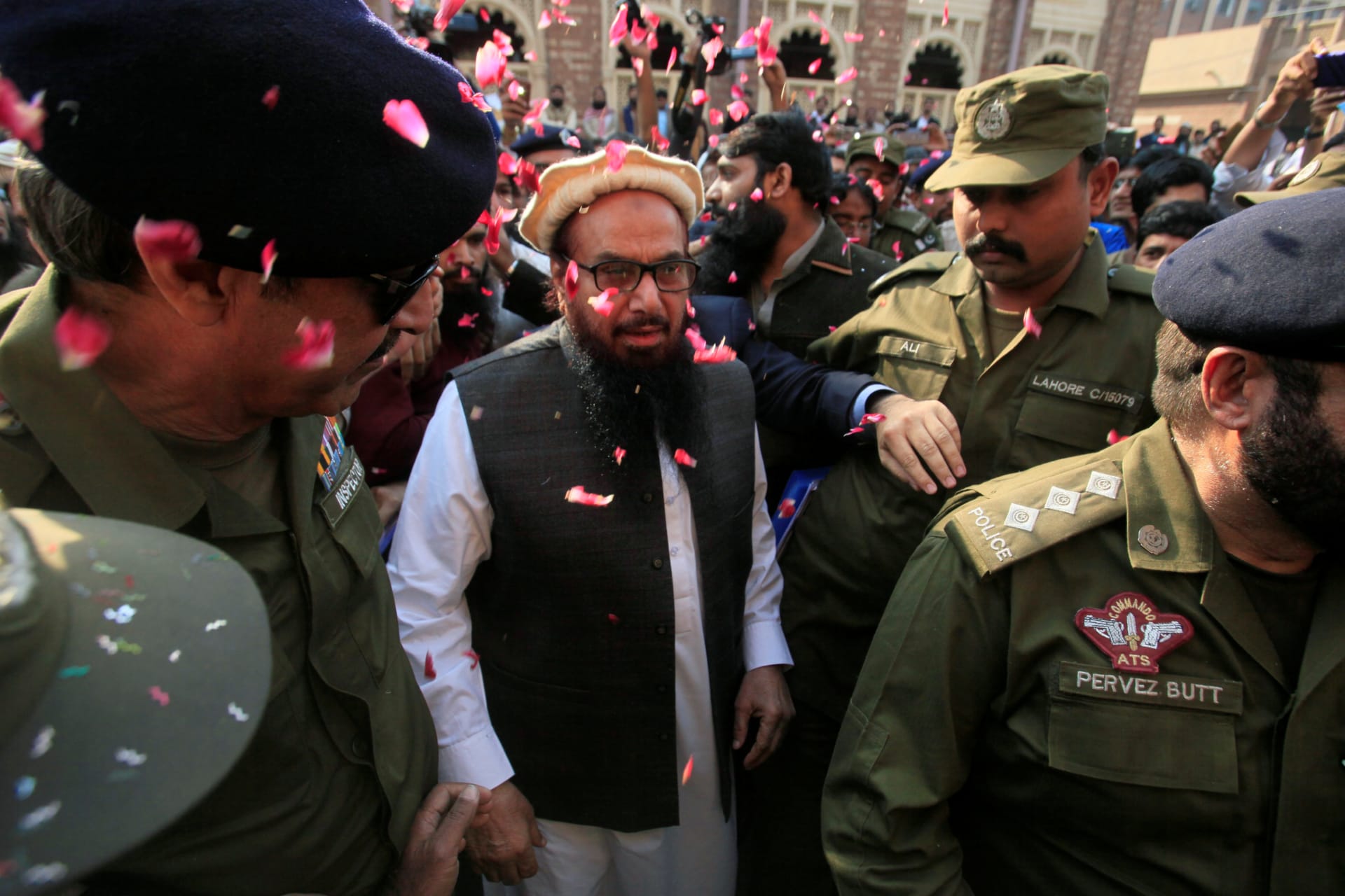 <p>File photo: Supporters shower Hafiz Saeed with flower petals as he walks to court in Lahore, Pakistan, in November 2017. The court released him from house arrest.</p>
