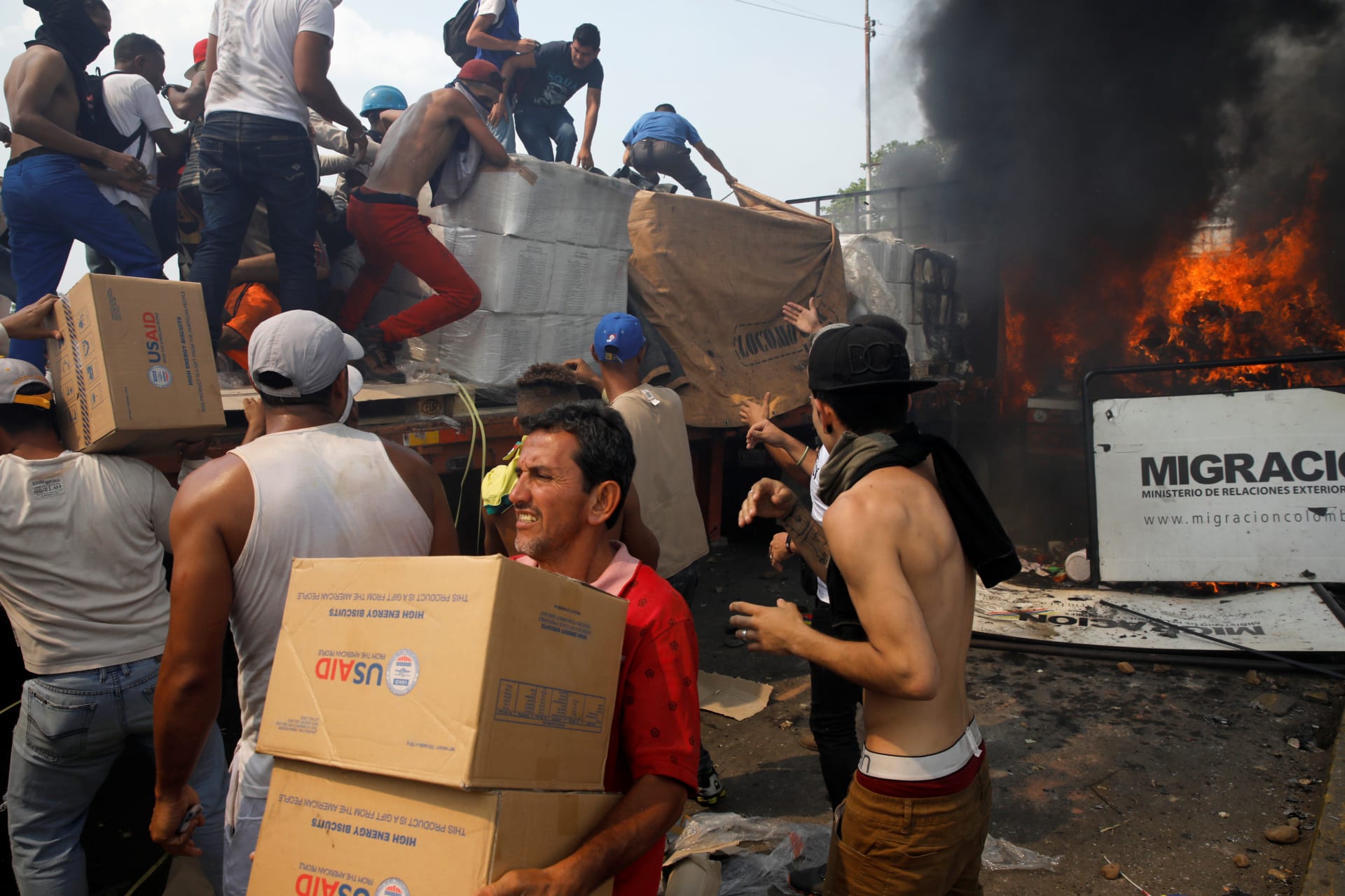 <p>Opposition supporters unload humanitarian aid from a truck that was set on fire after clashes between opposition supporters and Venezuela’s security forces on the border line as seen from Cucuta, Colombia, on February 23, 2019.</p>

