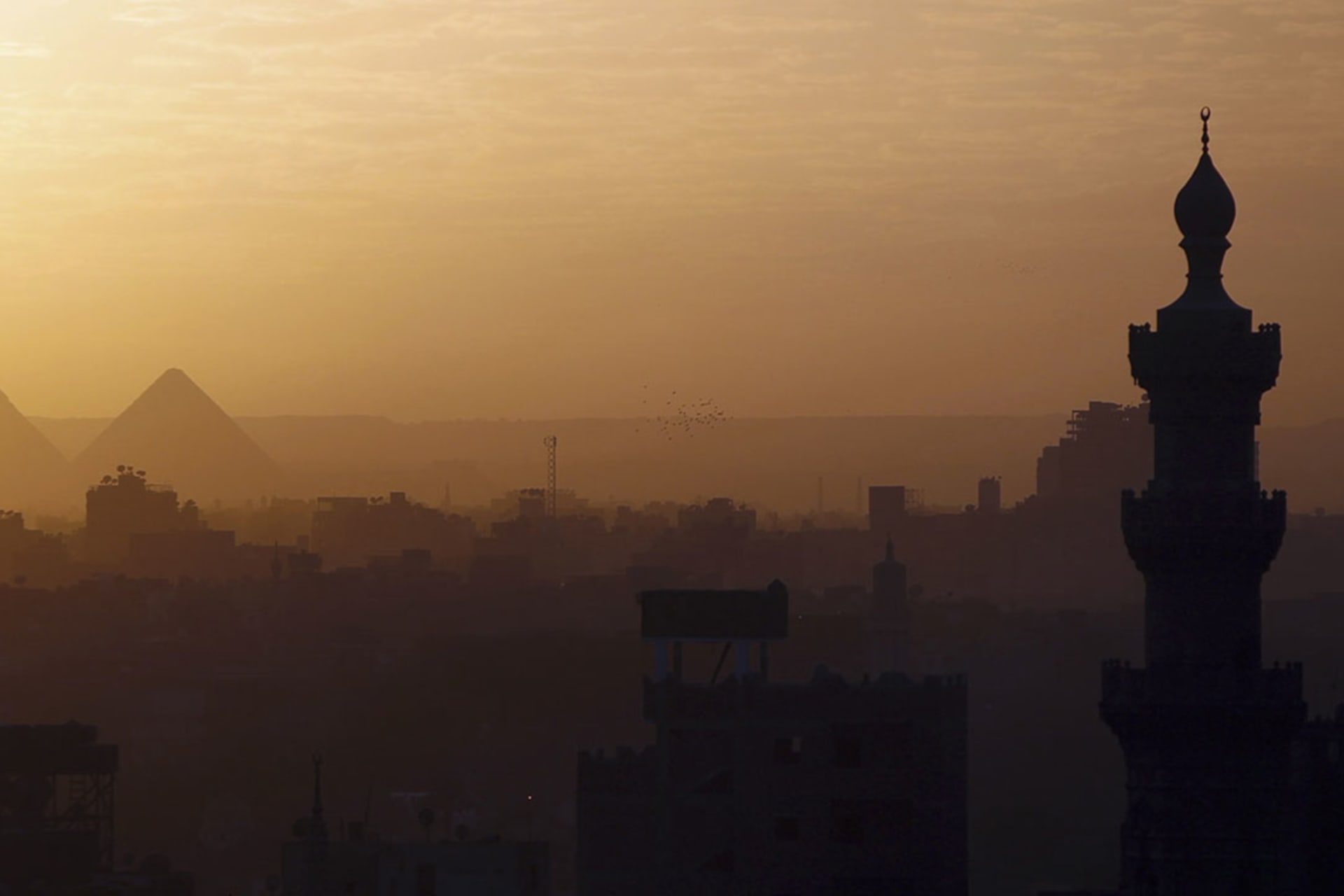 <p>A view of mosques and the great pyramids before sunset in Cairo.</p>