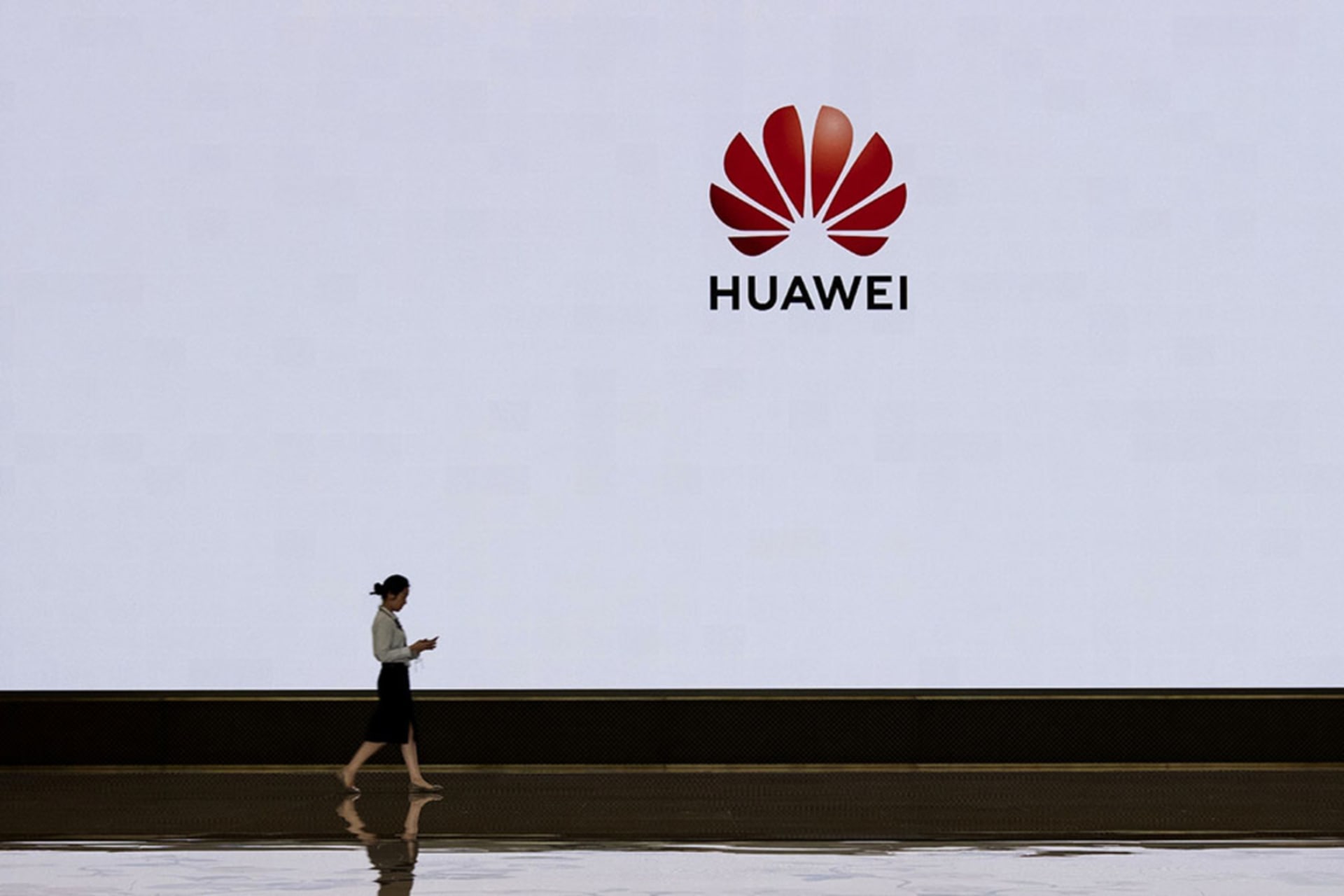 <p>A Huawei employee walks by a screen displaying the company’s logo at its Shenzhen headquarters.</p>
