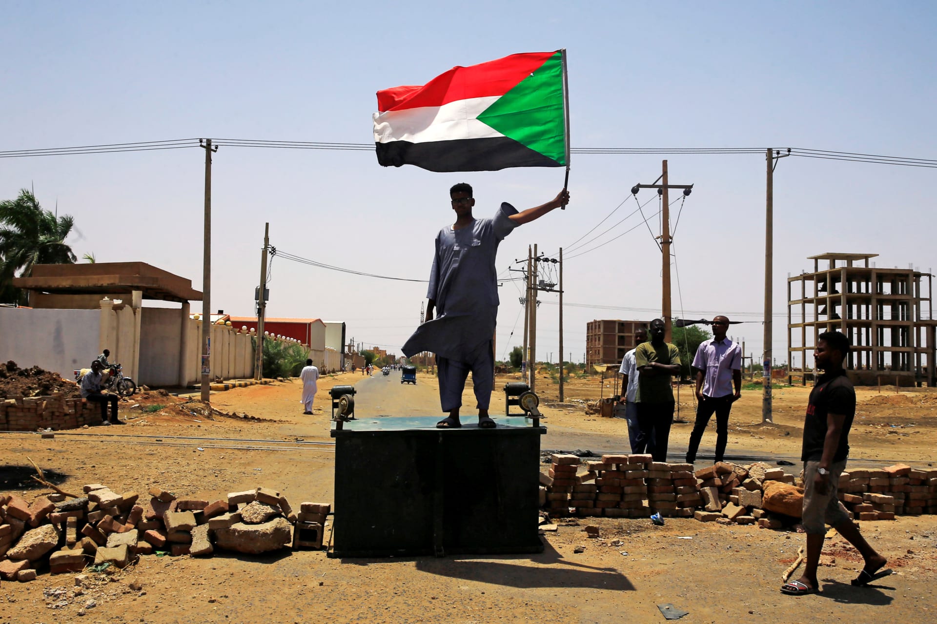 <p>A Sudanese protester holds a national flag as he stands on a barricade along a street, demanding that the country’s Transitional Military Council hand over power to civilians, in Khartoum, Sudan, on June 5, 2019. </p>
