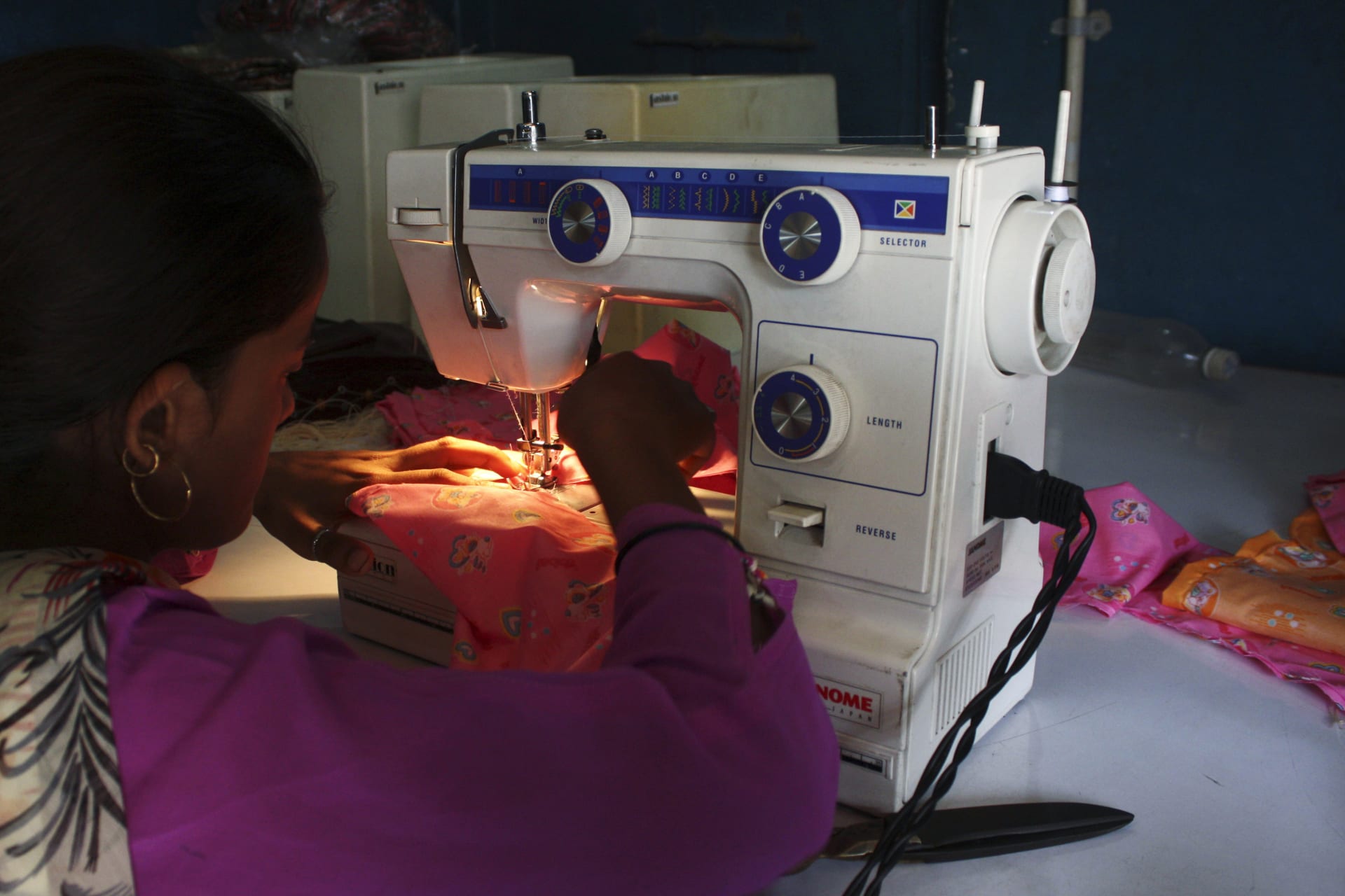 <p>A woman sews clothes on a sewing machine driven by solar energy in India, September 10, 2009.</p>
