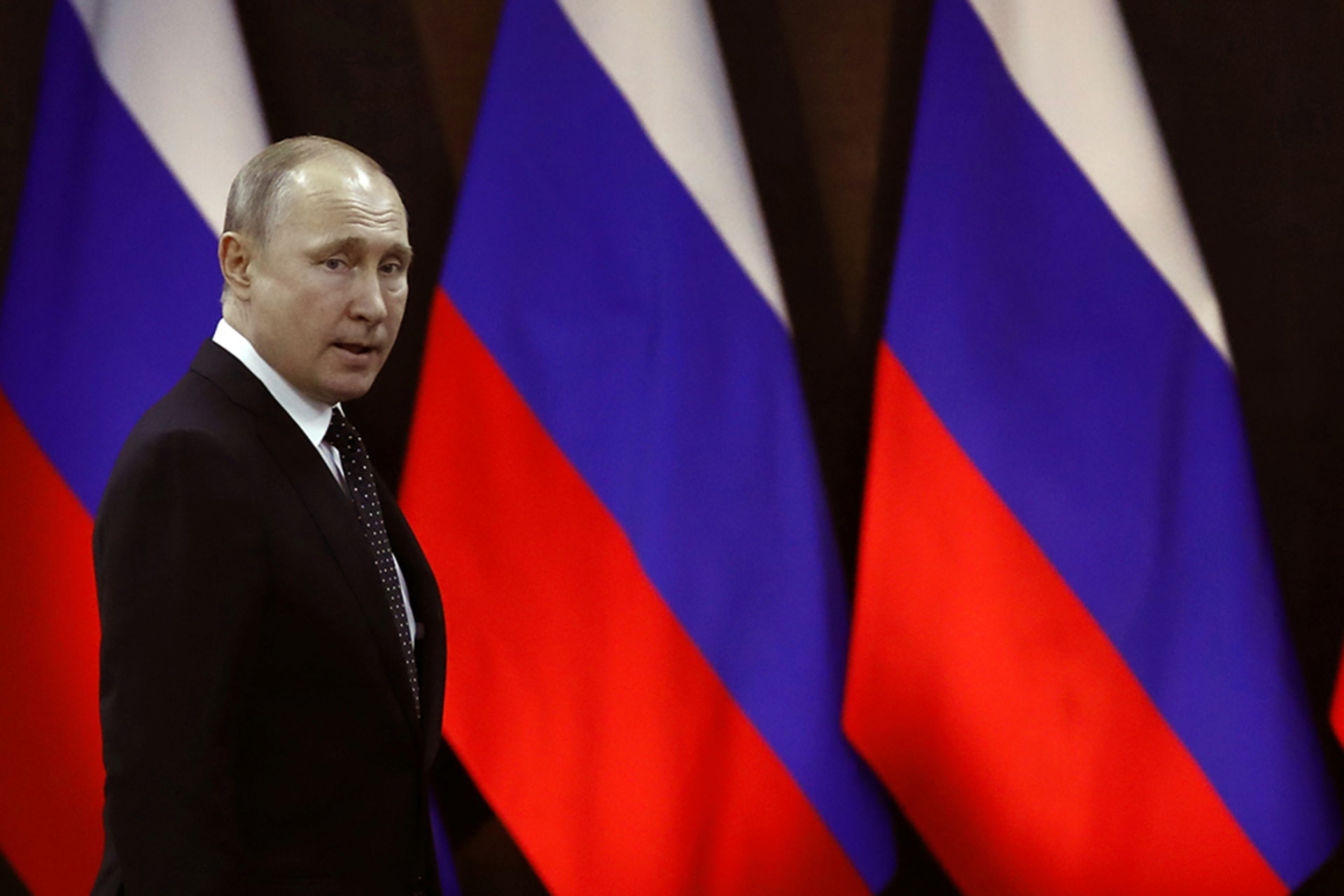 <p>Russian President Vladimir Putin walks past Russian flags in April 2019.</p>
