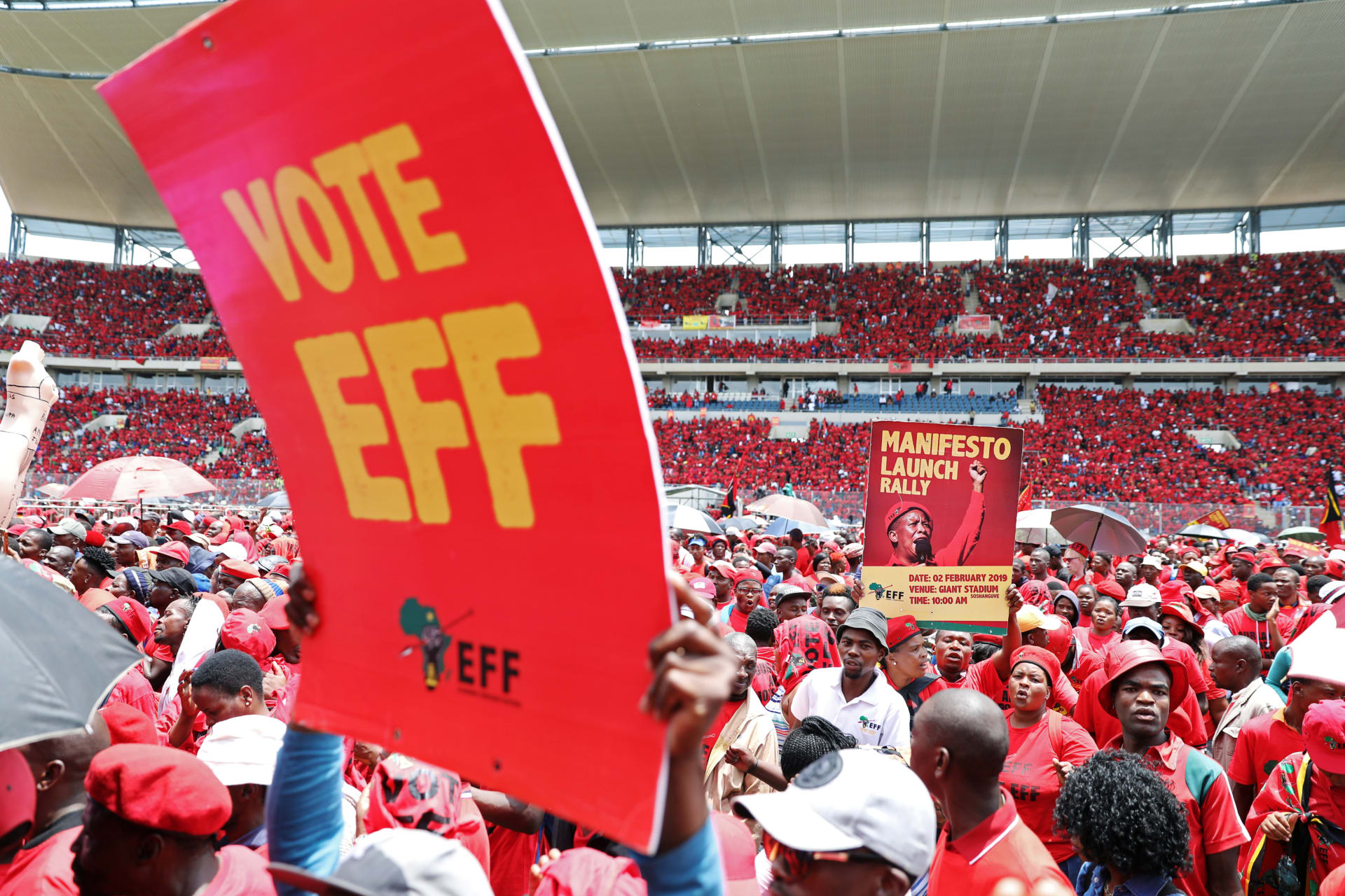 <p>Supporters of South Africa’s radical left-wing party, the Economic Freedom Fighters (EFF), hold a placard during the launch of the party’s election manifesto in Soshanguve, near Pretoria, South Africa, on February 2, 2019. </p>
