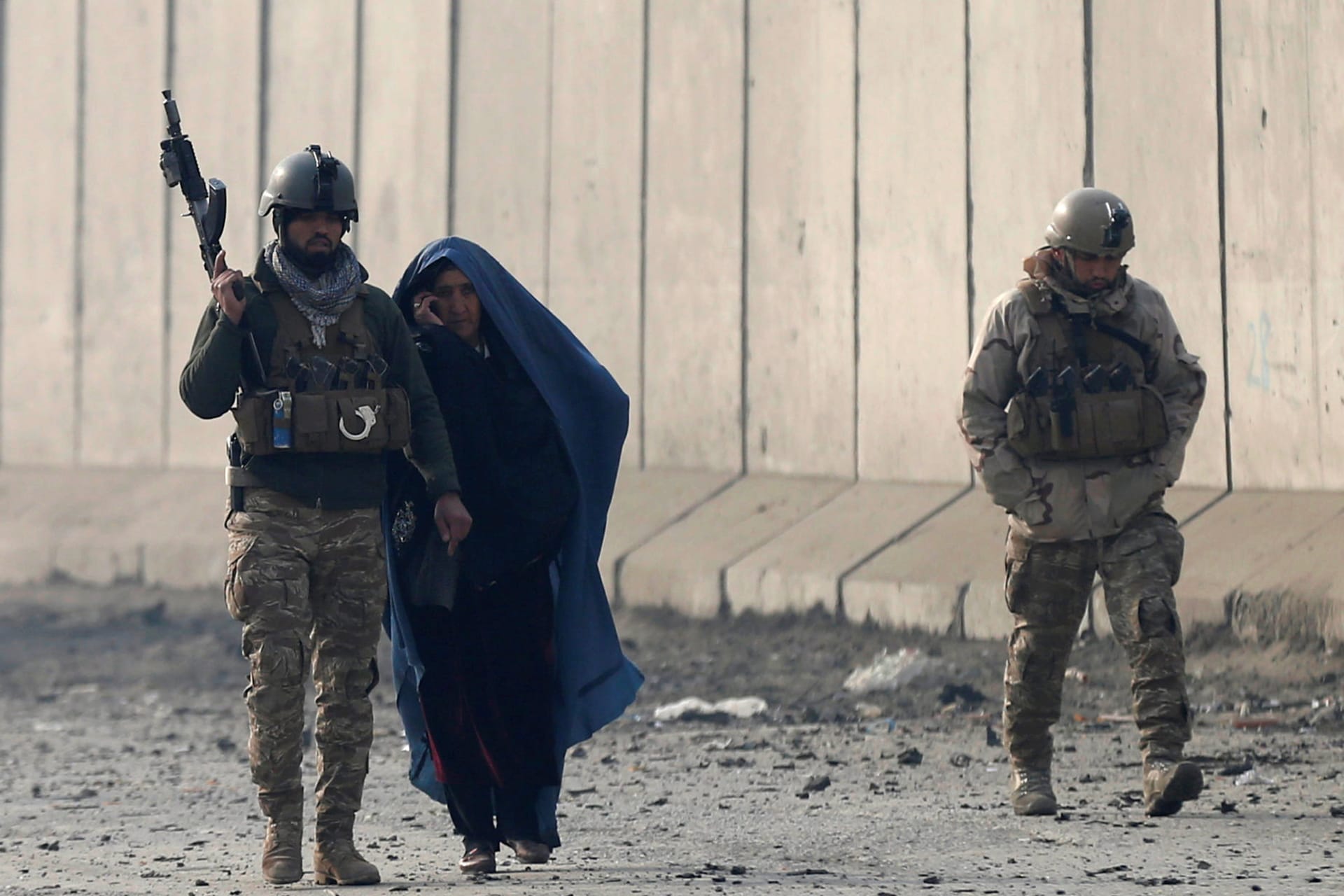 <p>Afghan security forces escort a woman at the site of a car bomb blast in Kabul, Afghanistan, 2019.</p>

