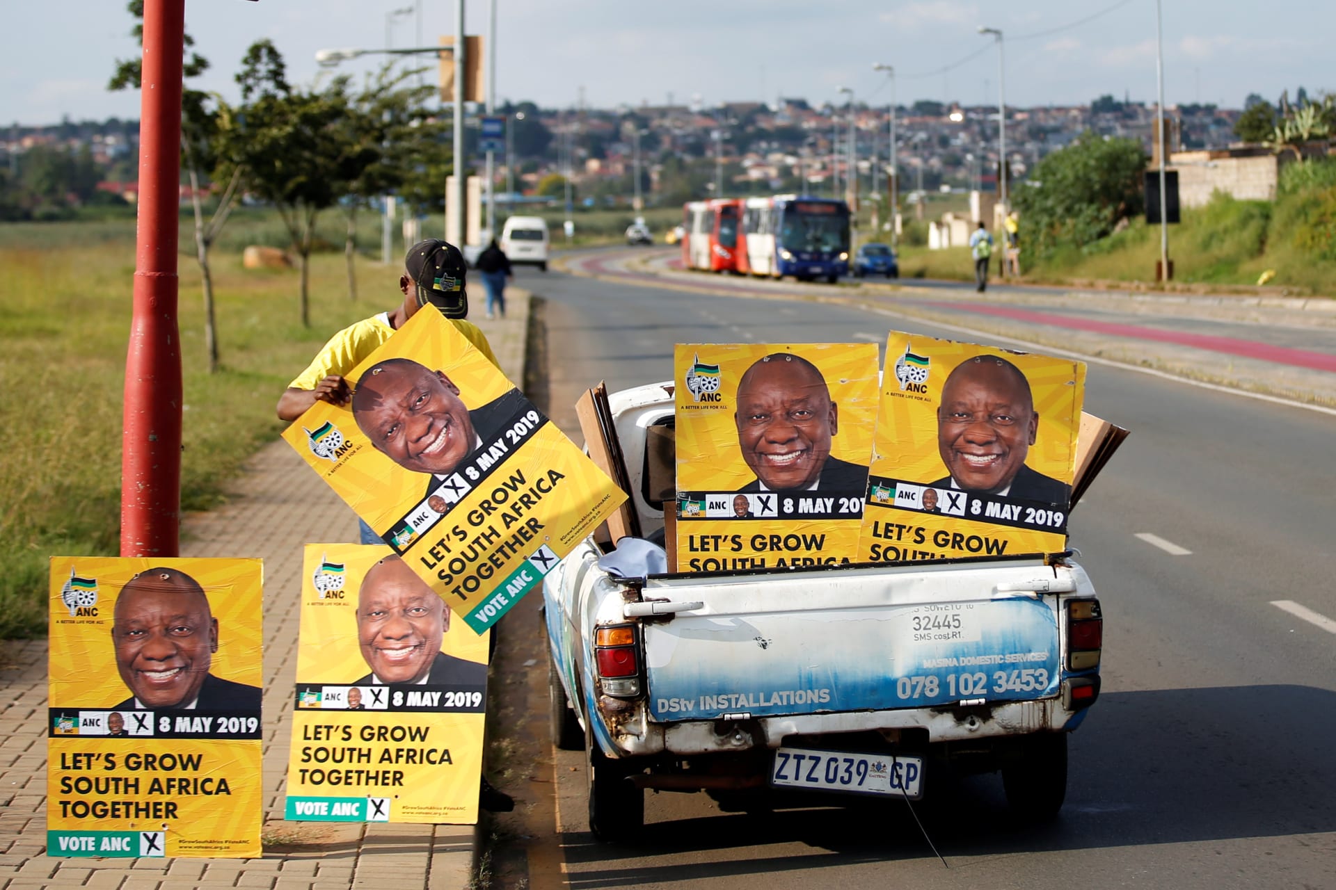<p>Musa Masina lines up election posters with the face of ANC president Cyril Ramaphosa, before hanging them on street poles in Soweto, South Africa, on March 12, 2019.</p>
