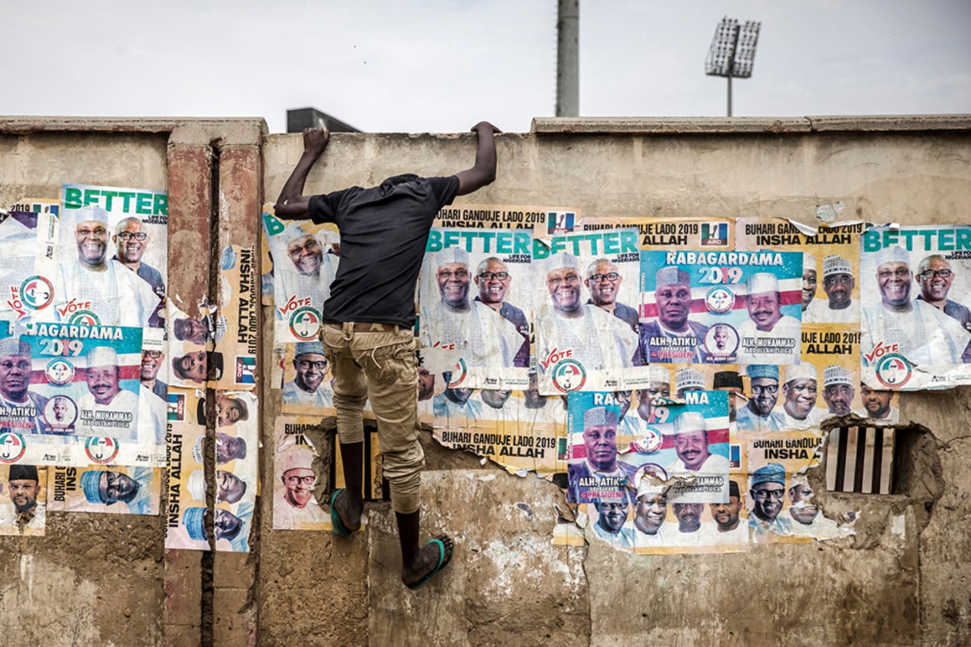<p>A young man climbs up a wall plastered with election posters during a rally in Kano to celebrate President Muhammadu Buhari’s reelection.</p>
