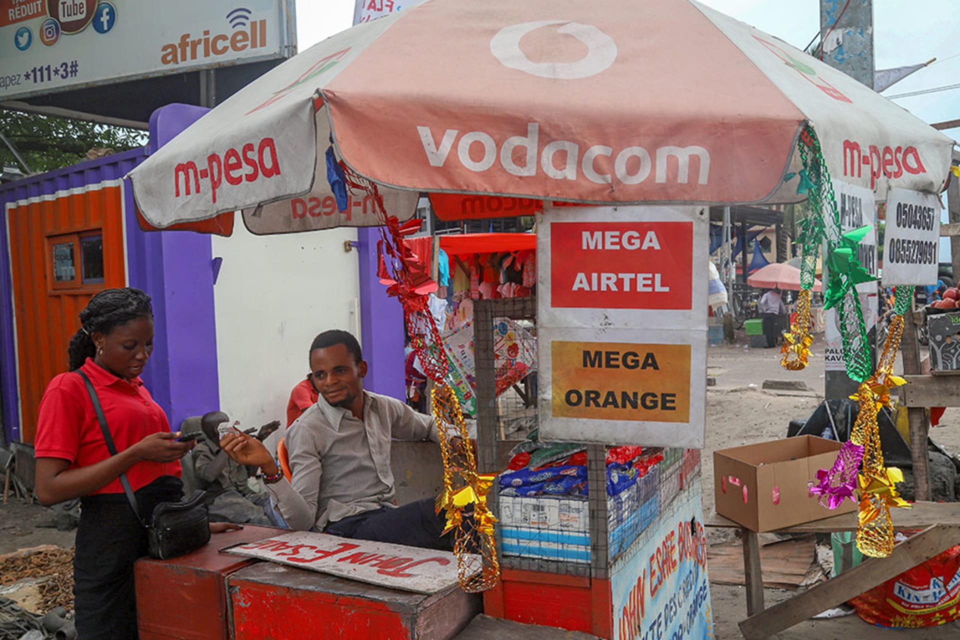 <p>A vendor assists a client to recharge her cell phone airtime at an open air stall in Kinshasa, Democratic Republic of Congo, on January 1, 2019.</p>