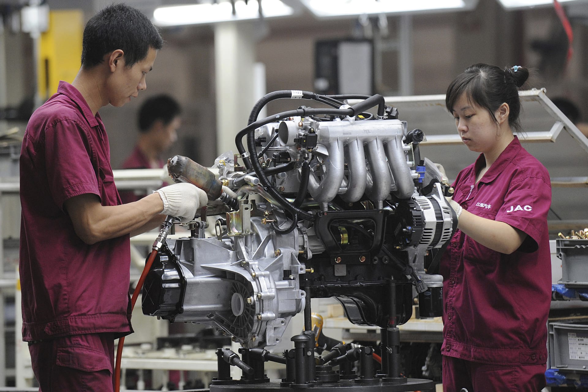 <p>Employees assemble an engine at the production line of an automobile company in Anhui province, China. July 16, 2009.</p>

