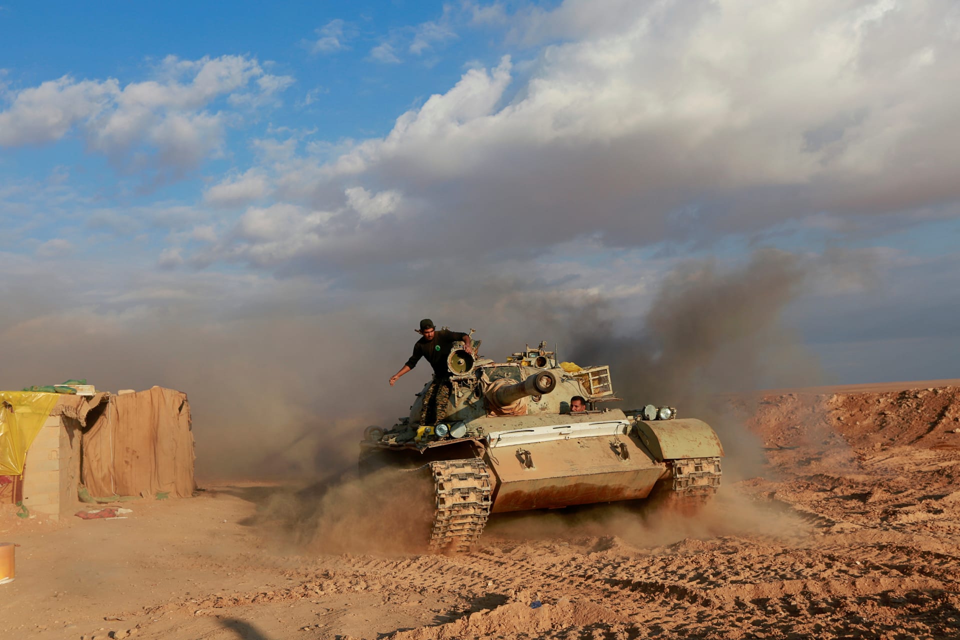 <p>Popular Mobilization Forces fighters ride in a tank near the Iraqi-Syrian border in al-Qaim, Iraq. </p>
