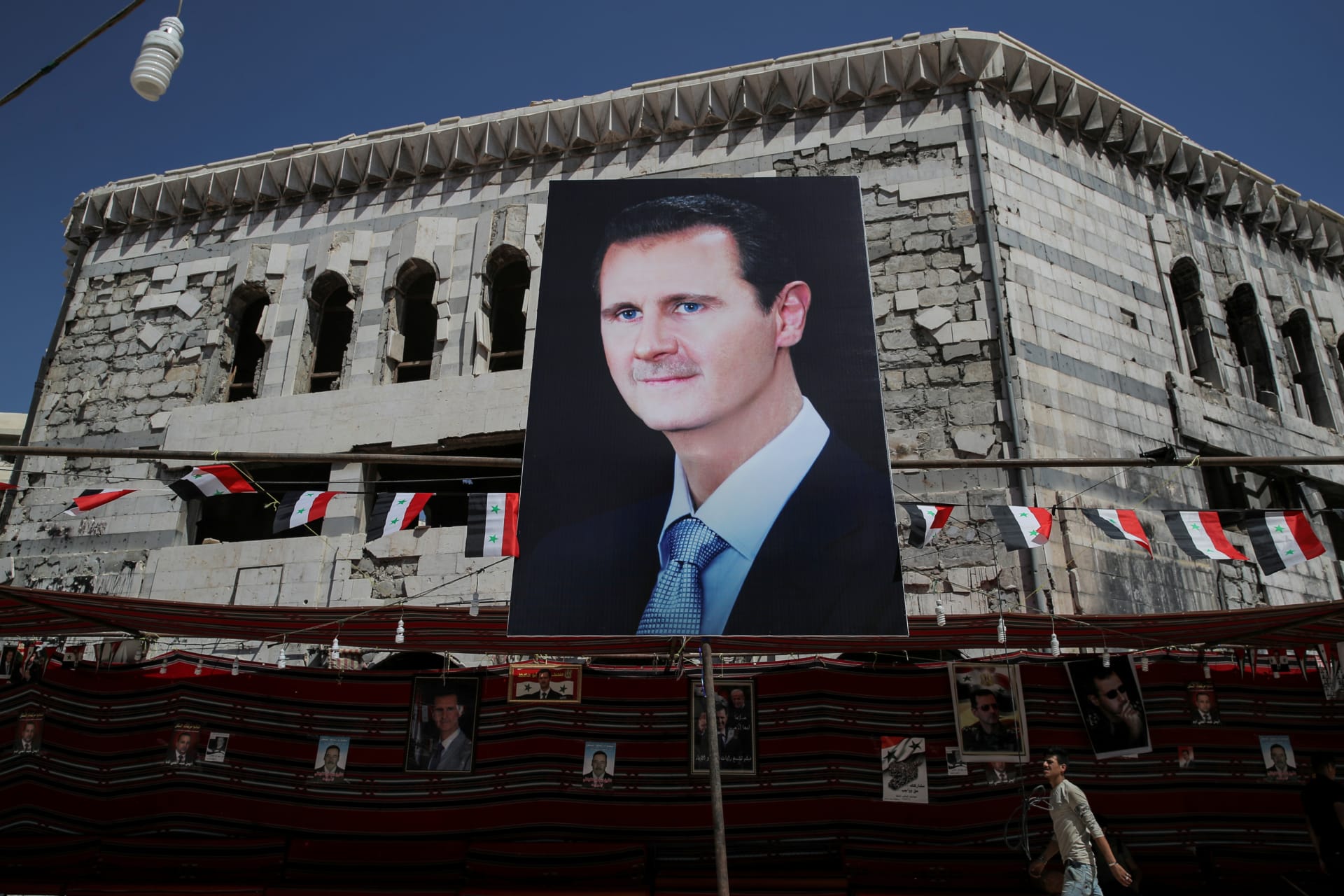 <p>A man walks past a banner depicting Syrian President Bashar al-Assad in Douma, outside Damascus, Syria, on September 17, 2018. </p>
