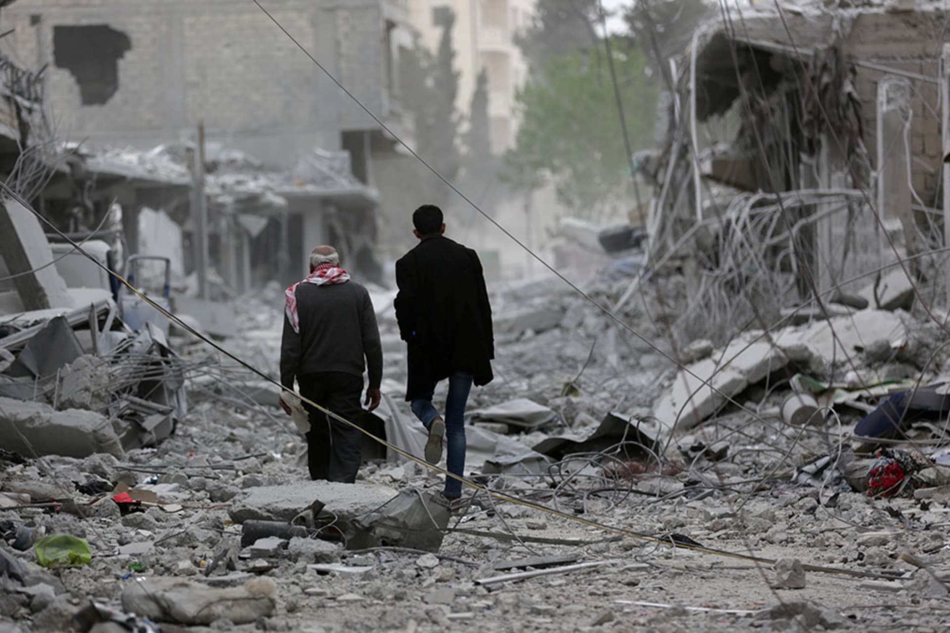 <p>Men walk through debris in the center of Afrin, Syria.</p>
