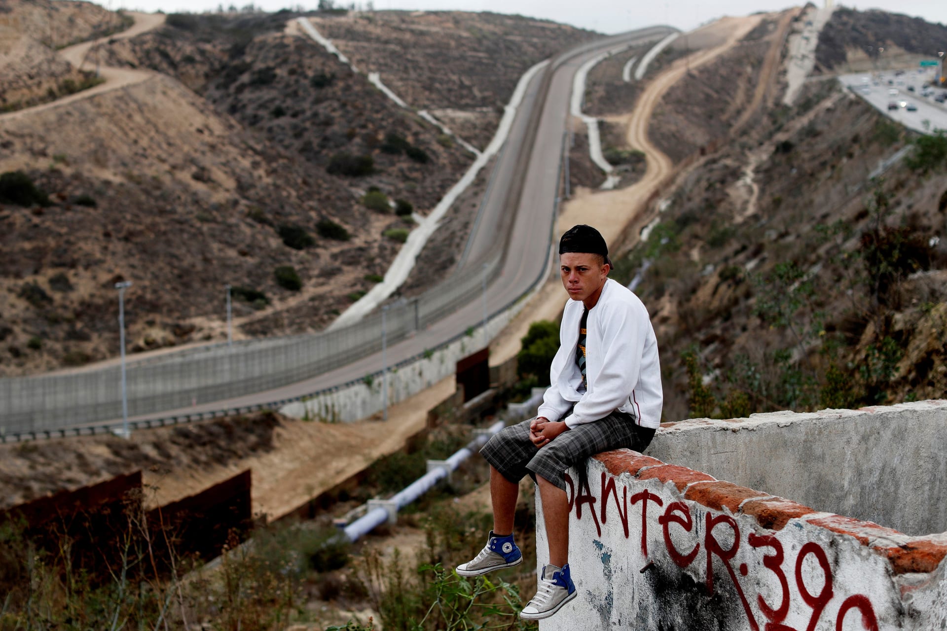 <p>Gerson Antonio Zaldivar, a migrant from Honduras, poses in front of the border wall between the U.S. and Mexico.</p>
