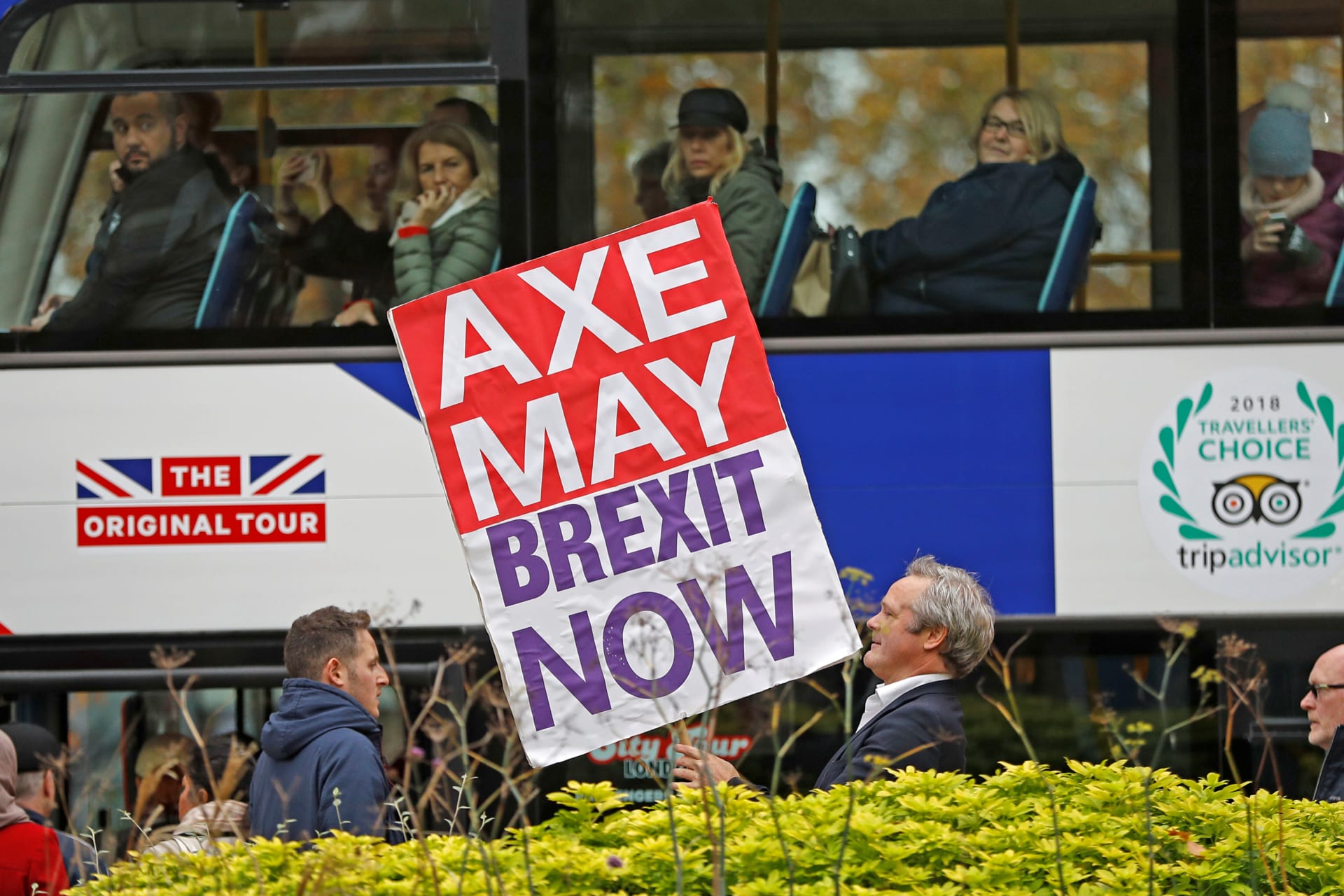 A pro-Brexit campaigner holds a placard as a tourist bus passes by in Westminster London.