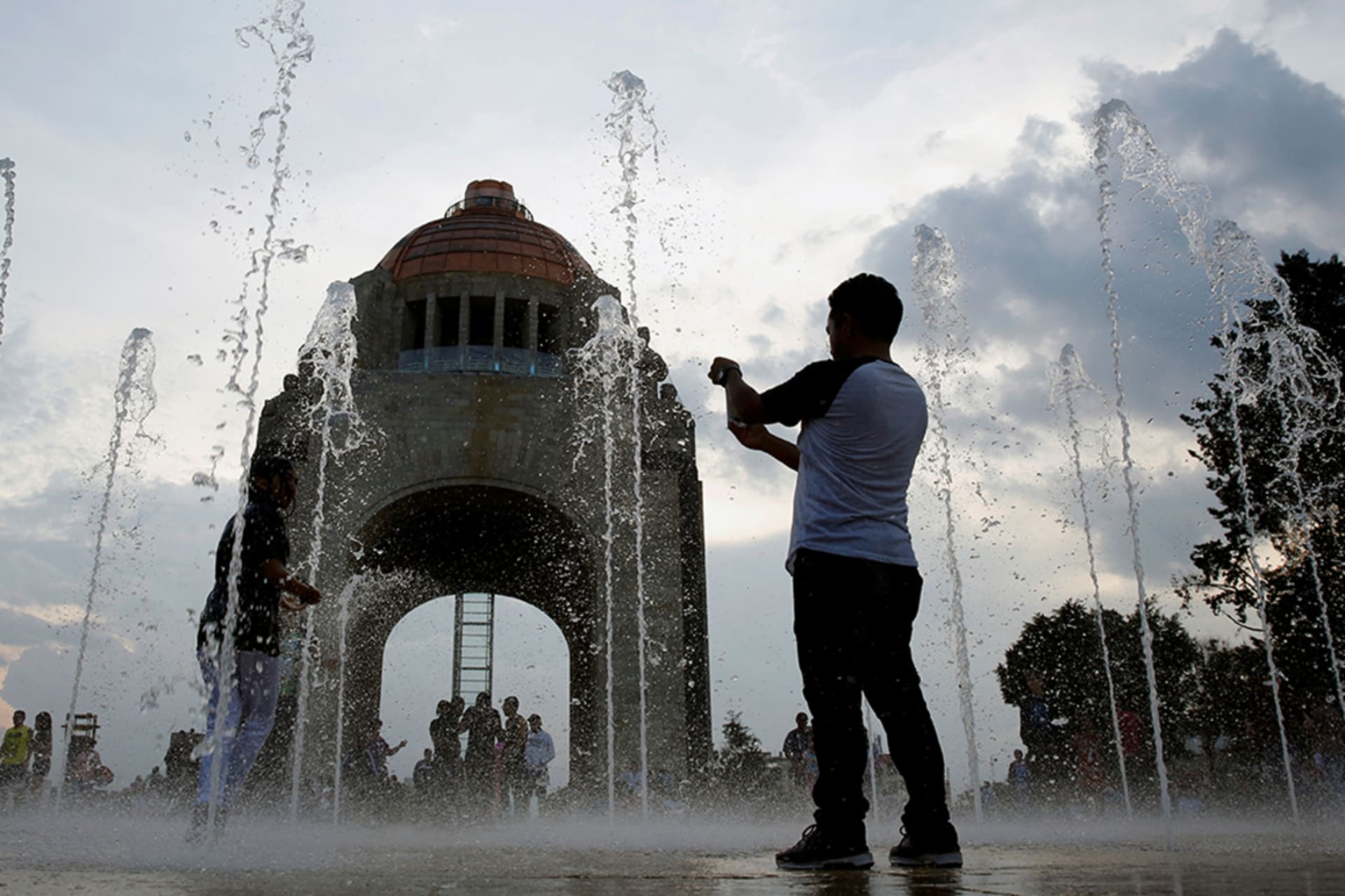 <p>A man takes a picture by a fountain at the Monument of the Revolution in Mexico City.</p>
