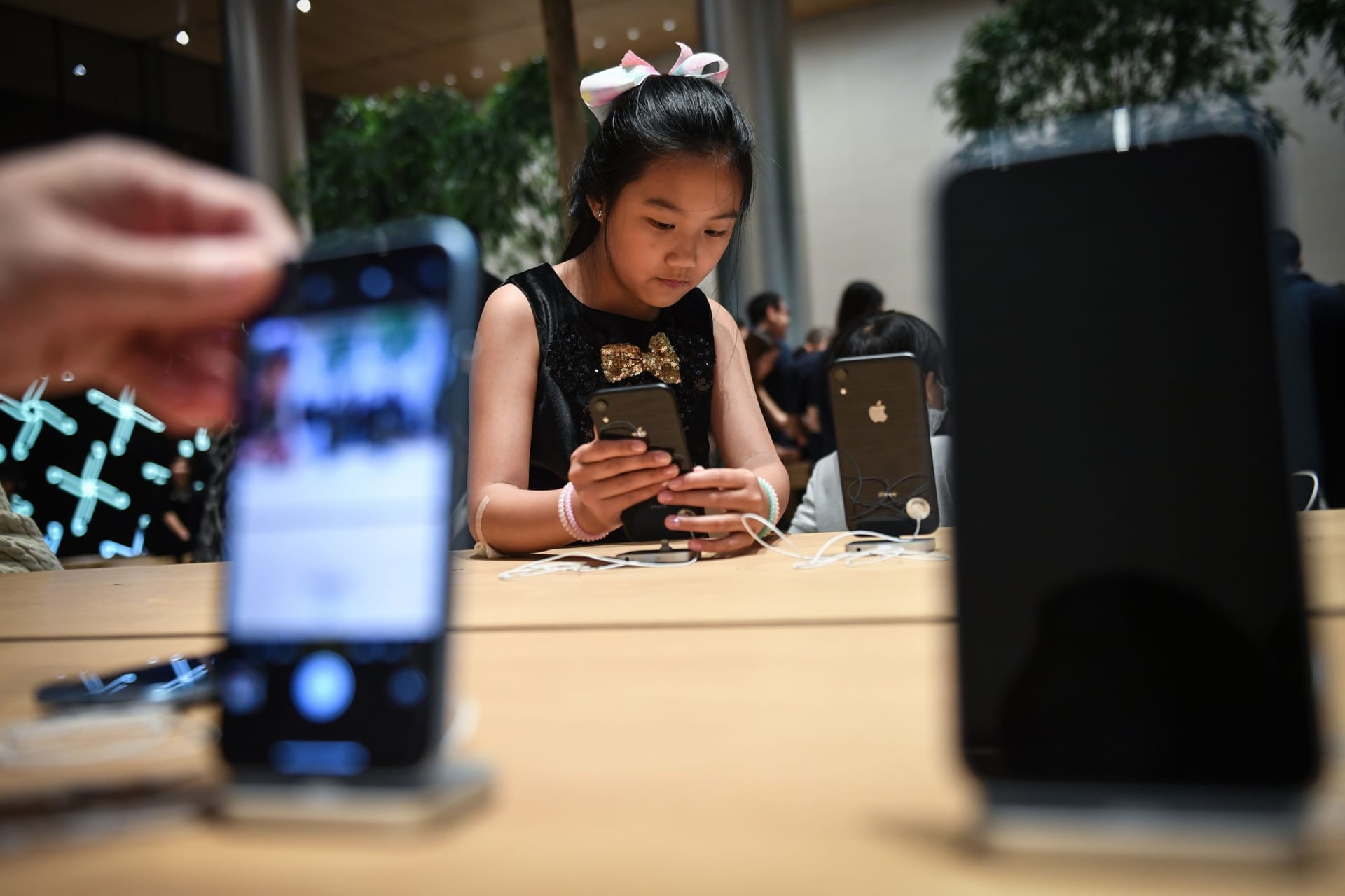 <p>Young girl checks out an iPhone in November 2018.</p>
