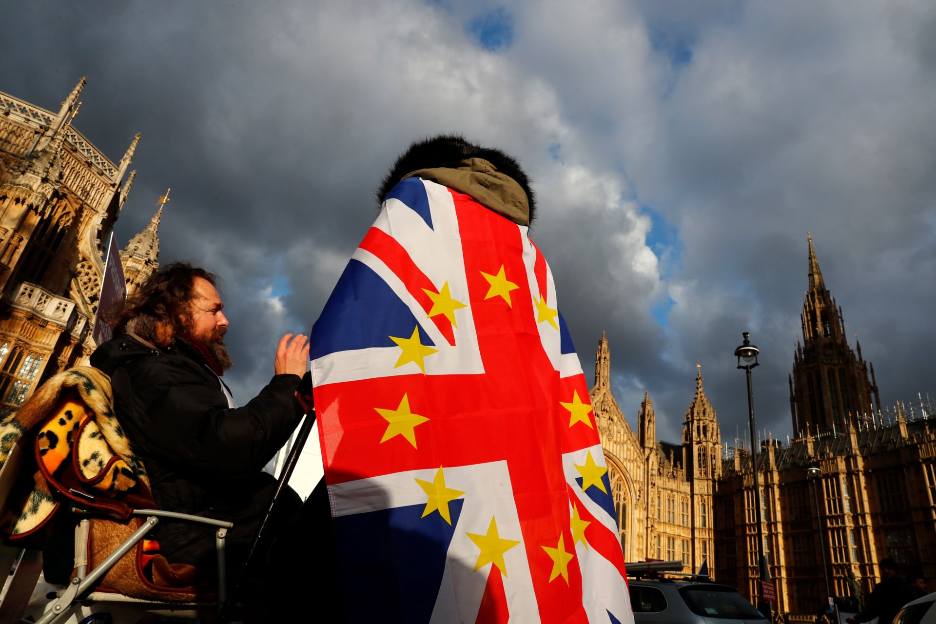 <p>An anti-Brexit demonstrator wears a Union flag decorated with the stars of the EU flag opposite the Houses of Parliament in London, Britain.</p>
