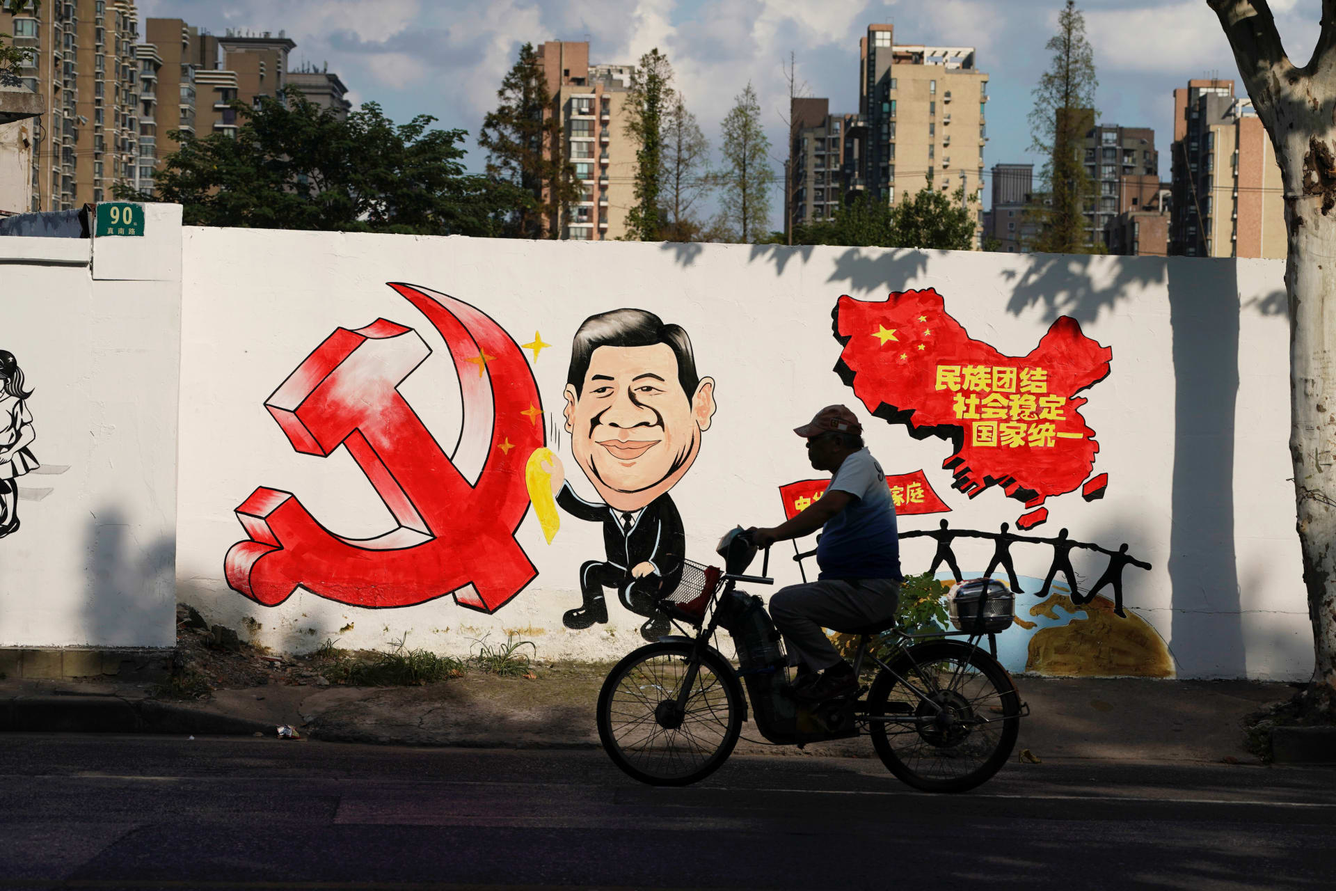 <p>A man rides a bicycle next to a mural showing an image of Chinese President Xi Jinping along a street in Shanghai, China September 28, 2018. </p>

