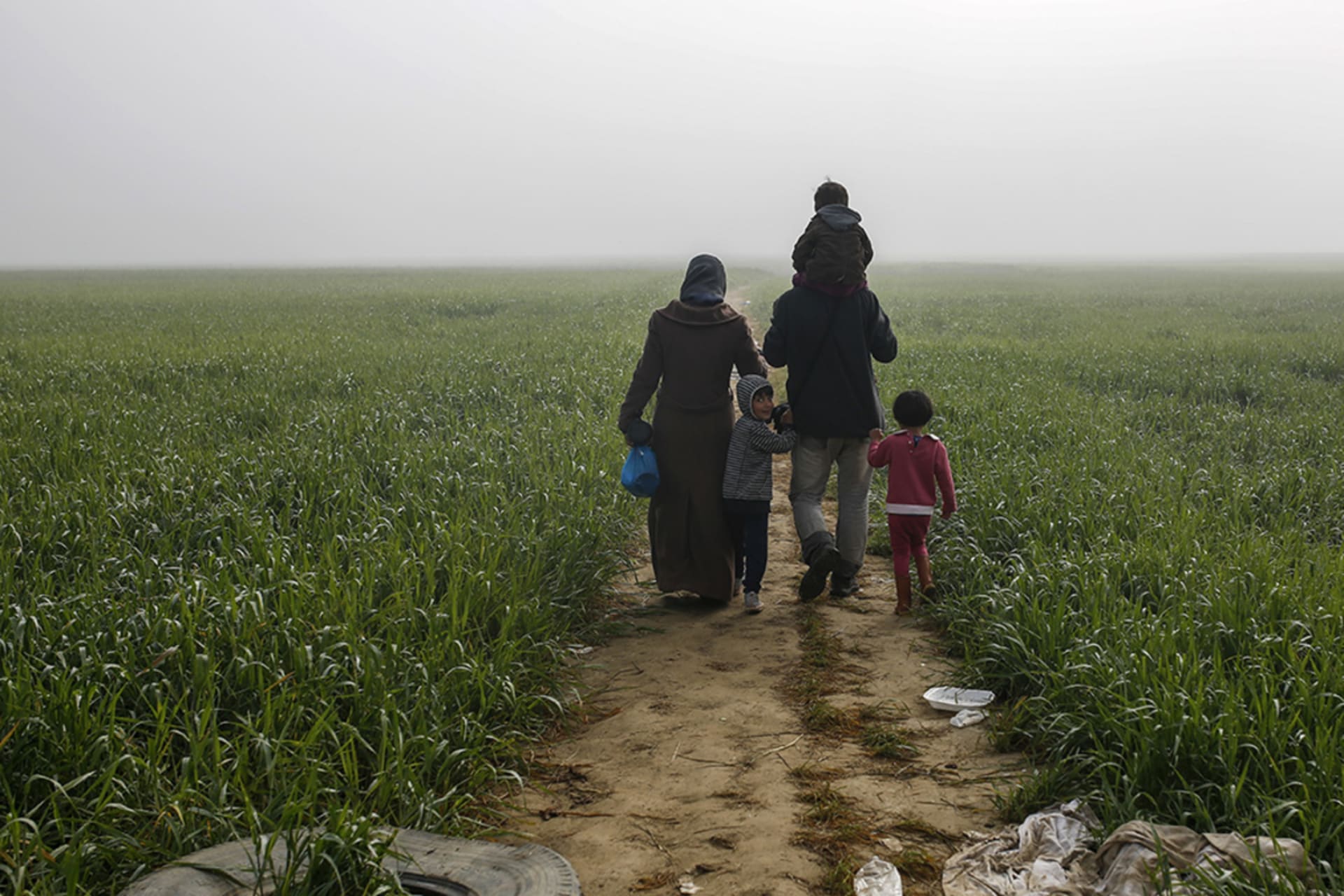 <p>A family walks through a camp for migrants and refugees outside Idomeni, Greece, along the border with Macedonia, in 2016.</p>

