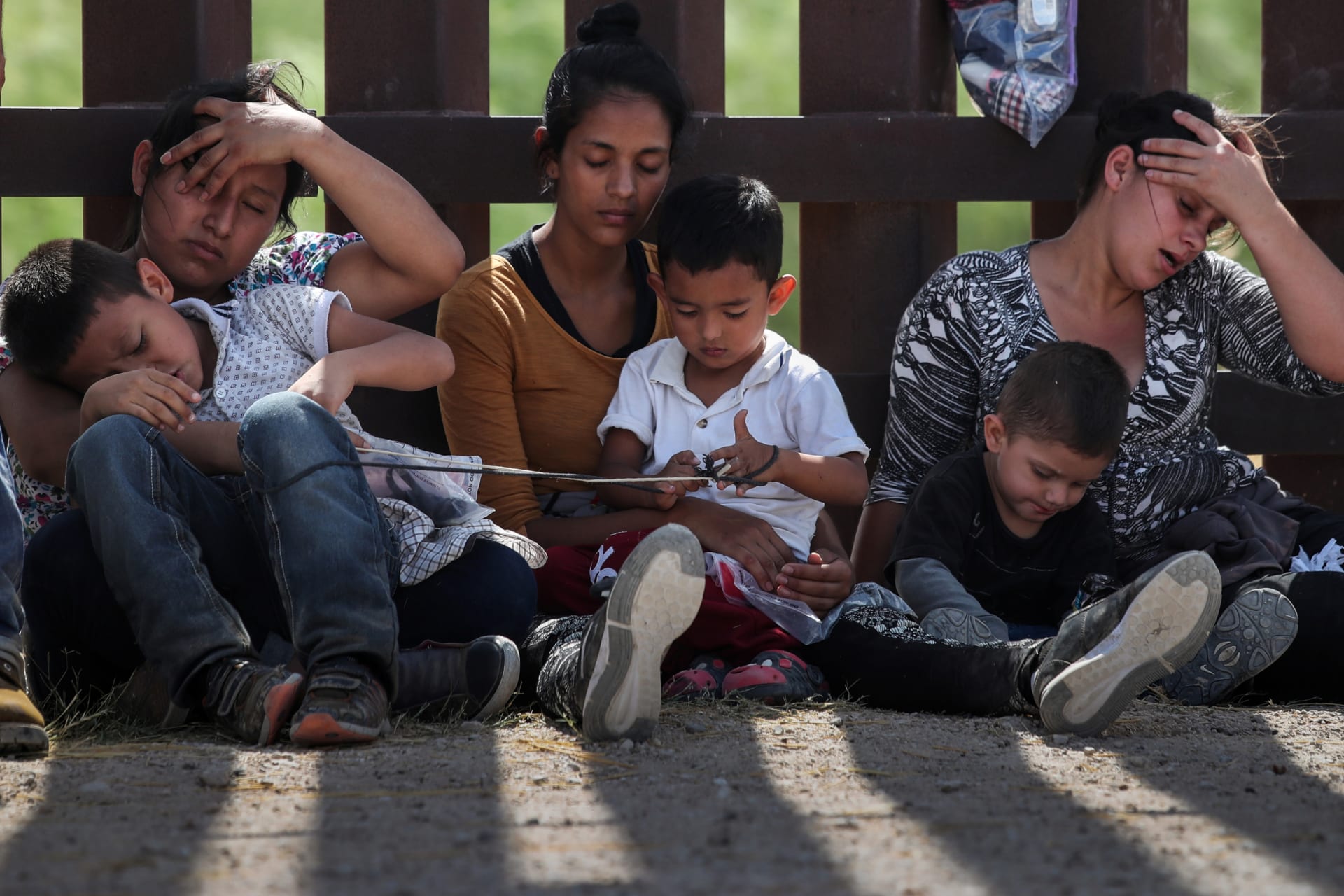 <p>Immigrant women hold their children along the border wall as they await apprehension after crossing into the U.S. from Mexico. </p>

