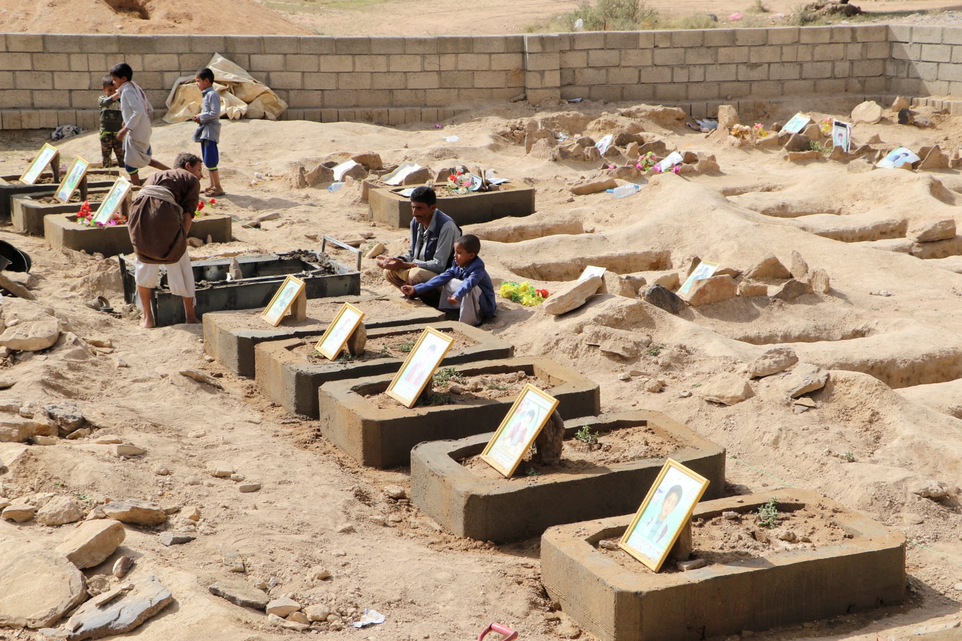 <p>Abdullah al-Khawlani sits by his son Waleed’s grave, who was killed by last month’s Saudi-led air strike that killed dozens, including children in Saada, Yemen September 4, 2018. His other son, Hafidh, who survived the strike, sits next to him.</p>
