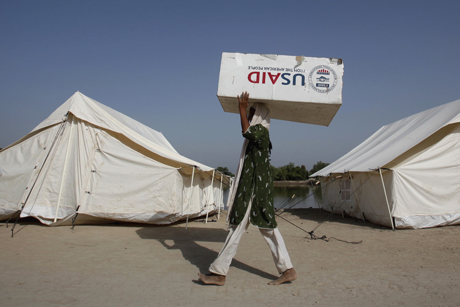 <p>A woman displaced by floods uses a box from the U.S. Agency for International Development, the U.S. government’s main foreign aid agency, to move her belongings in Dadu, Pakistan, in 2010.</p>
