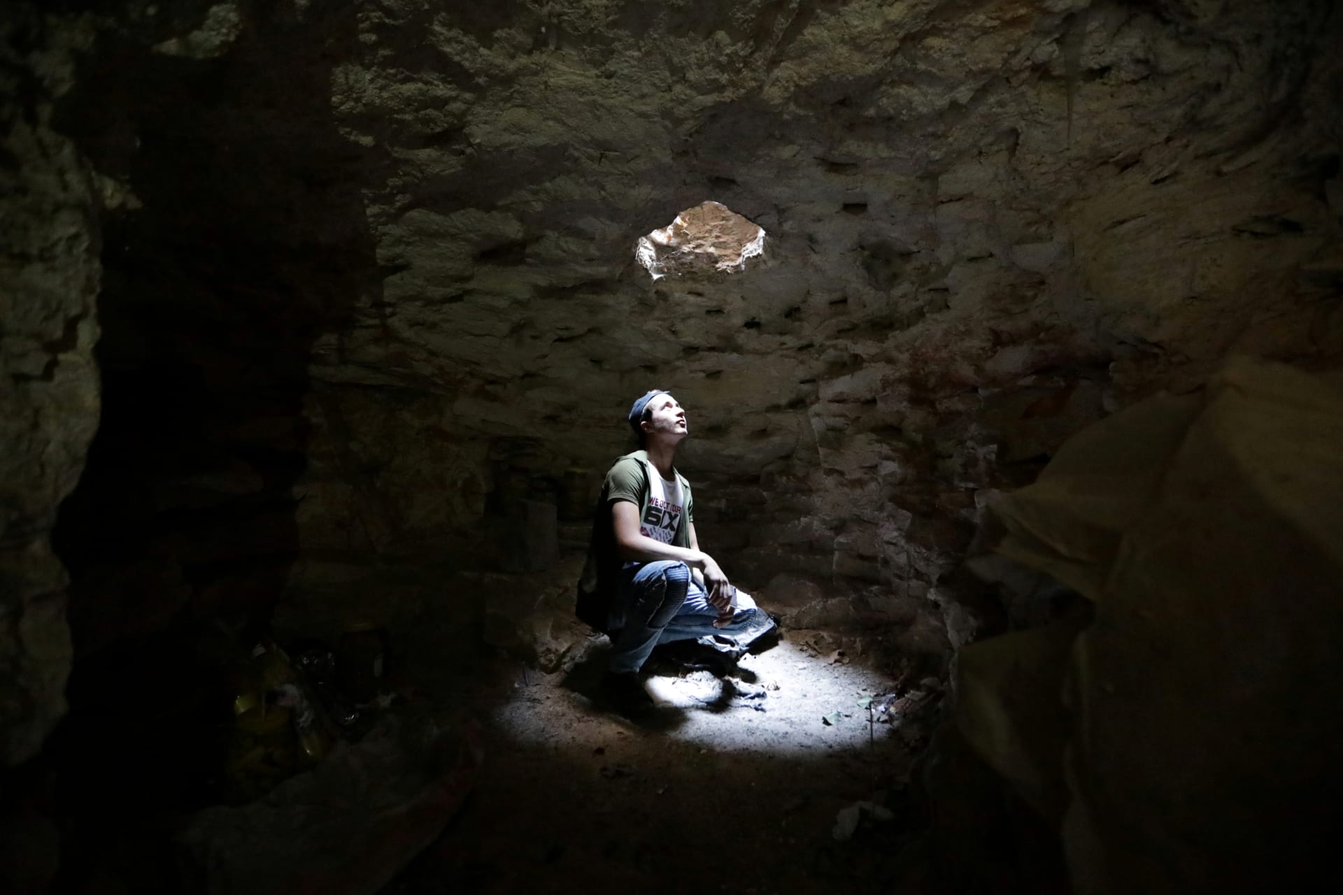 <p>A man looks at an opening from a makeshift shelter in an underground cave in Idlib, Syria, on September 3, 2018. </p>

