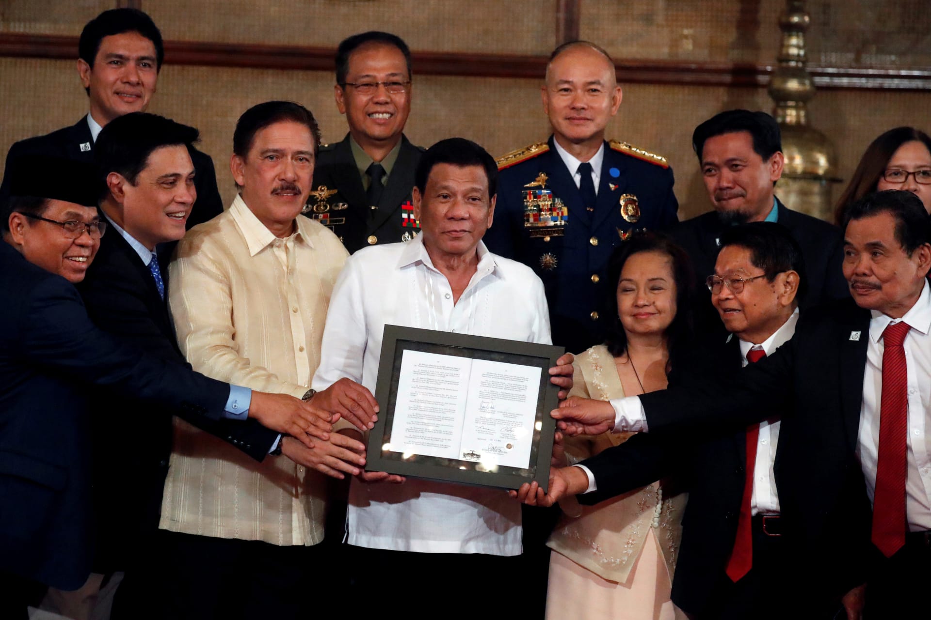 <p>President Rodrigo Duterte, Moro Islamic Liberation Front chairman Murad Ebrahim, and other government and military officials show a document containing a signed autonomy law during a ceremony in Manila, Philippines on August 6, 2018.</p>
