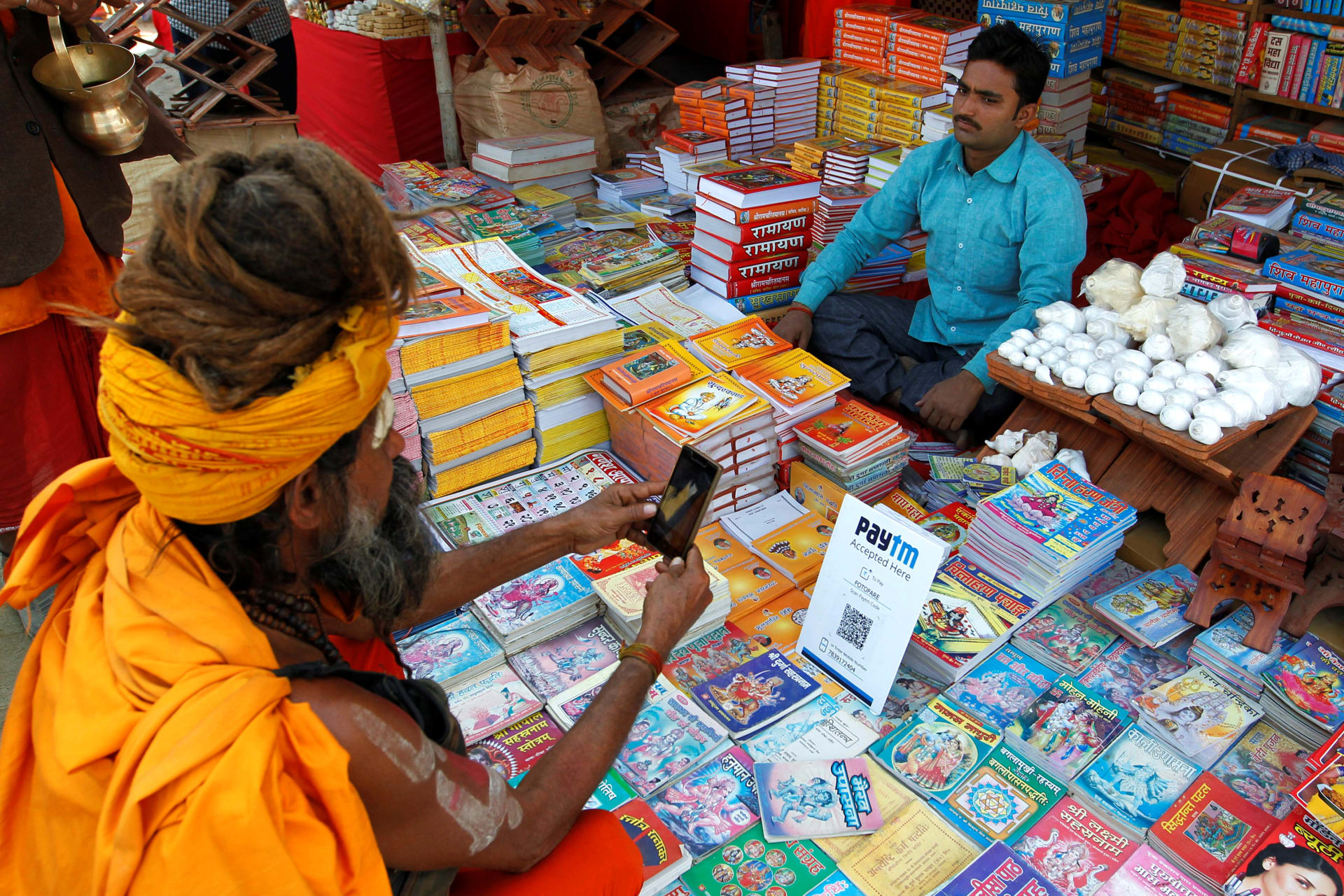 <p>A man pays a vendor through Paytm, a digital wallet company, after buying a book during the annual religious festival of Magh Mela in Allahabad, India on January 26, 2017.</p>