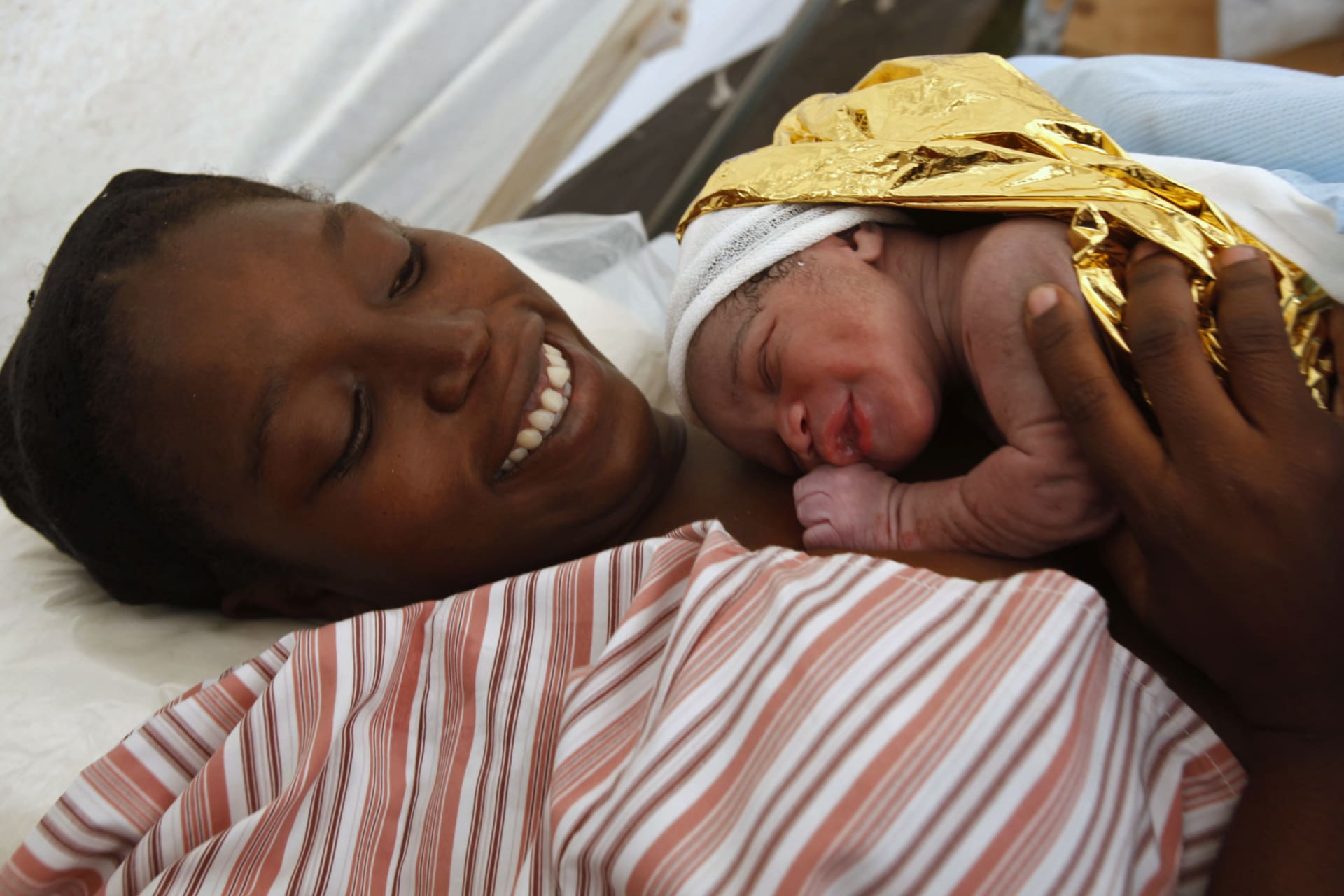 <p>Madame Marcus holds her five-minute-old baby boy after giving birth to her second child at a makeshift hospital run by B-FAST (Belgian First Aid and Support Team).</p>
