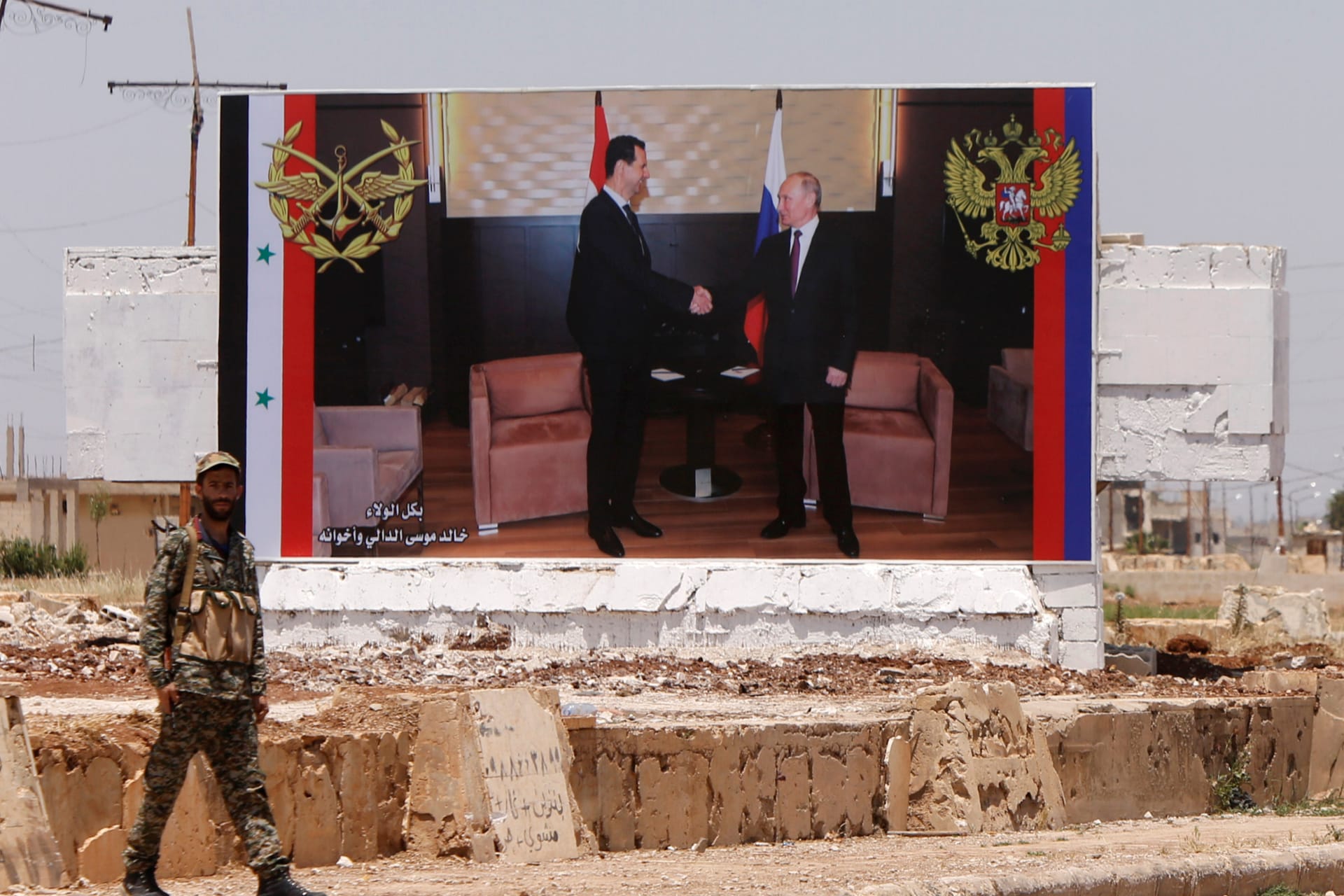 <p>A soldier stands guard near a poster of Syria’s President Bashar al Assad and his Russian counterpart Vladimir Putin during the re-opening of the road between Homs and Hama in Rastan, Syria, June 6, 2018.</p>
