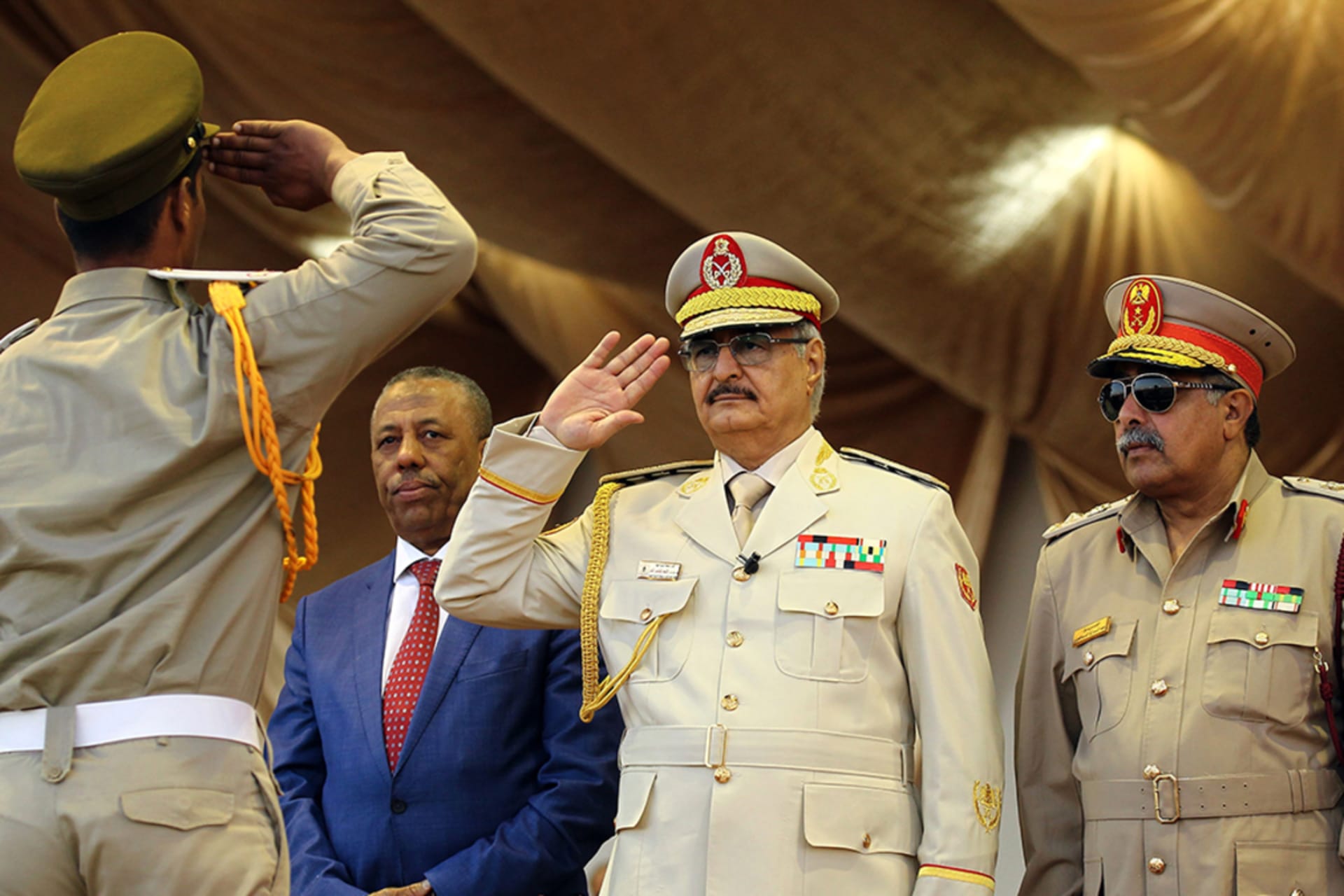 <p>Khalifa Haftar (C), leader of the Libyan National Army, salutes next to his Chief Of Staff Abdelrazak al-Nadhuri (R) and Libyan former prime minister Abdullah al-Thani</p>
